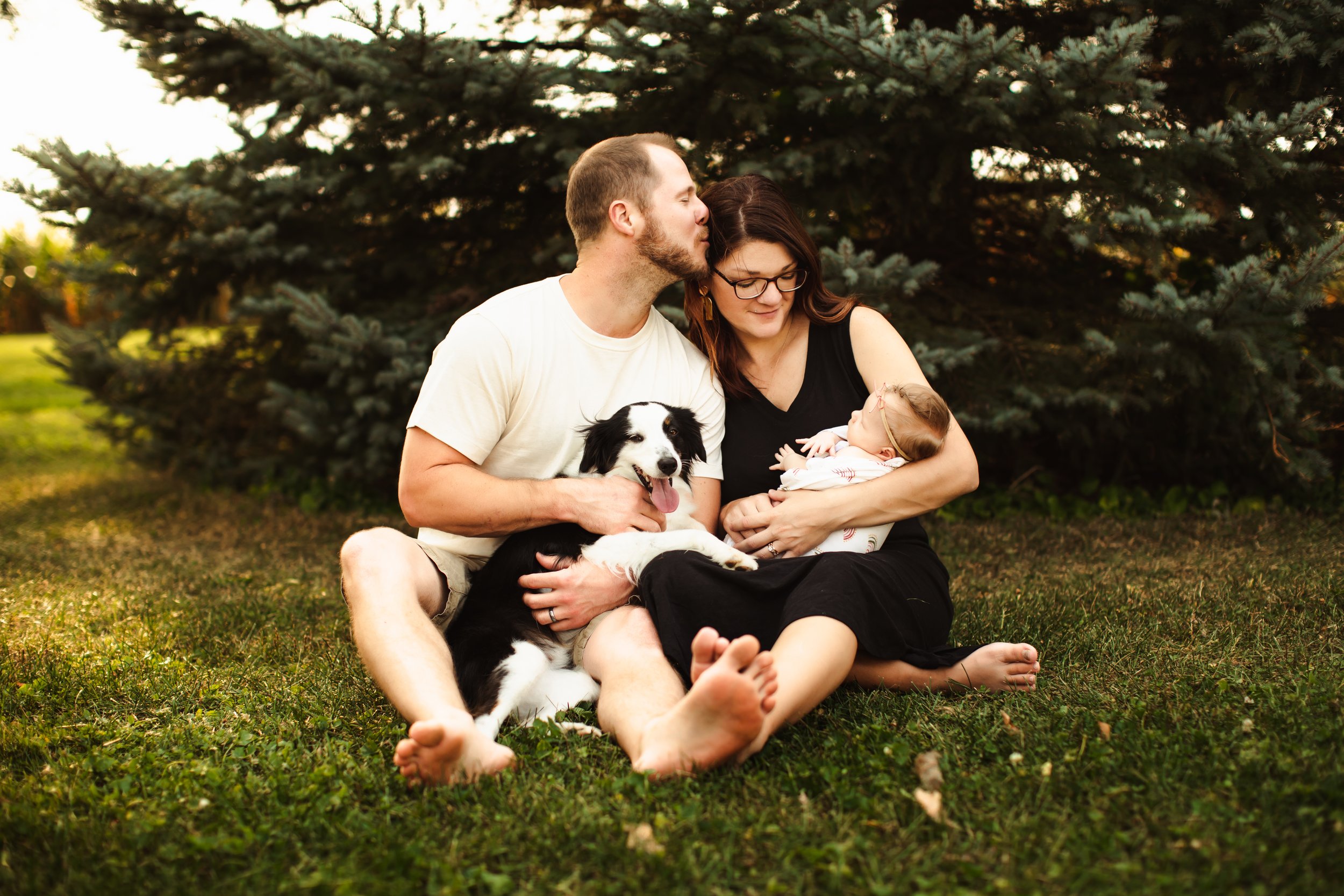  A family snuggles on their front lawn during their at home newborn photo shoot. mom dad dog and baby girl family of four Teala Ward Photography in Princeton Illinois #TealaWardPhotography #illinoisphotographer #princetonillinois  