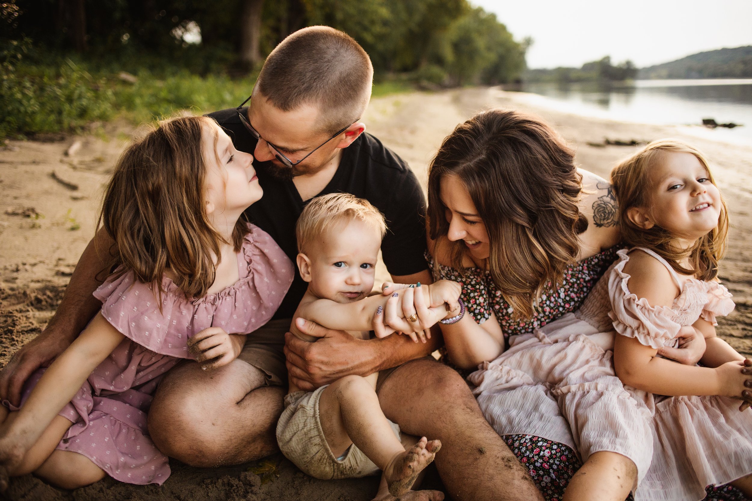  A family of five sits on the sand beach of the Illinois River and smiles at one another by Teala Ward Photography. three kids summer #TealaWardPhotography #TealaWardFamilies #IllinoisRiverPhotography #IllinoisFamilyPhotography #familylifestylepics 