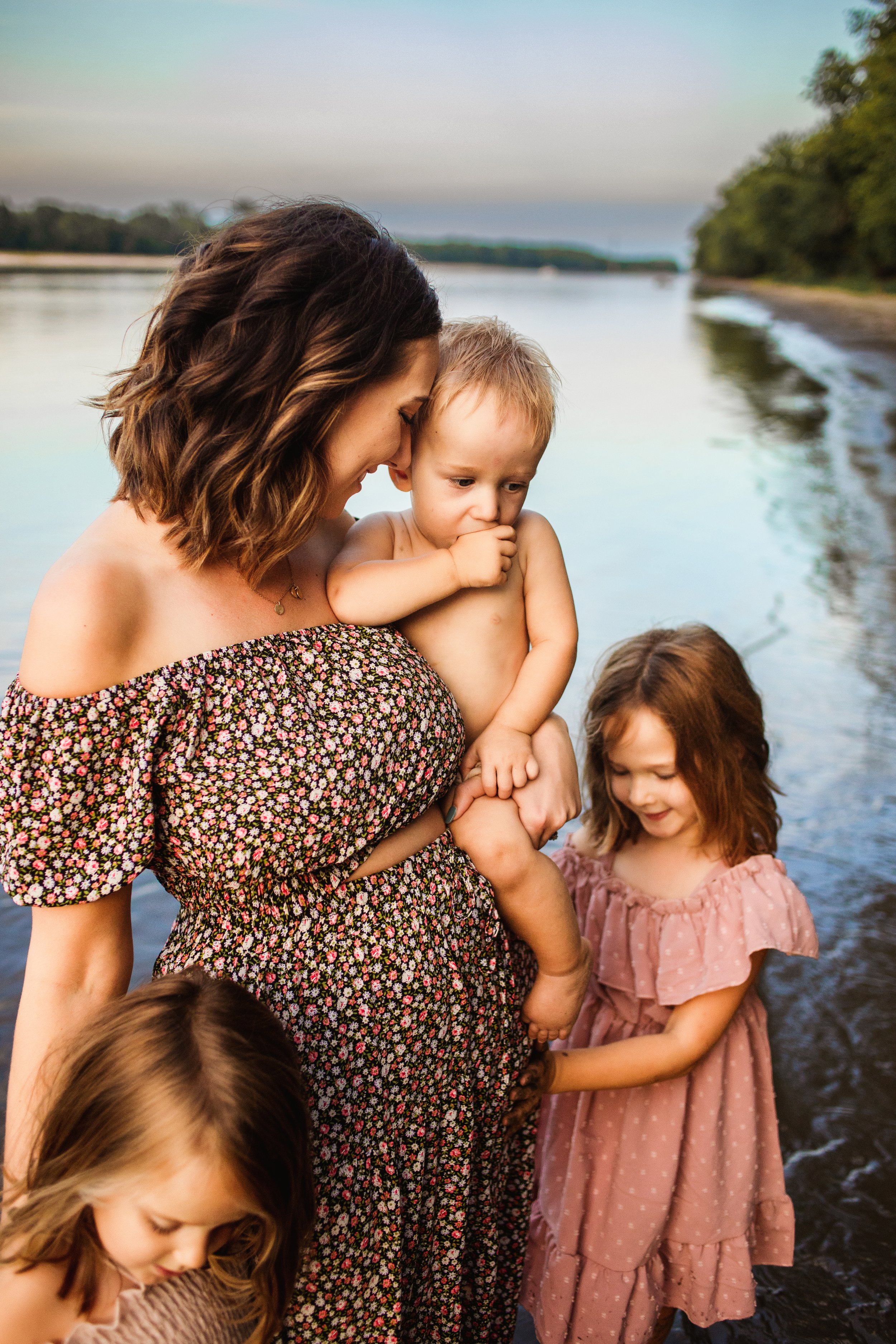  Teala Ward Photography captures a mother wearing an off-the-shoulder floral dress snuggling her children. motherhood dress #TealaWardPhotography #TealaWardFamilies #IllinoisRiverPhotography #IllinoisFamilyPhotography #familylifestylepics 