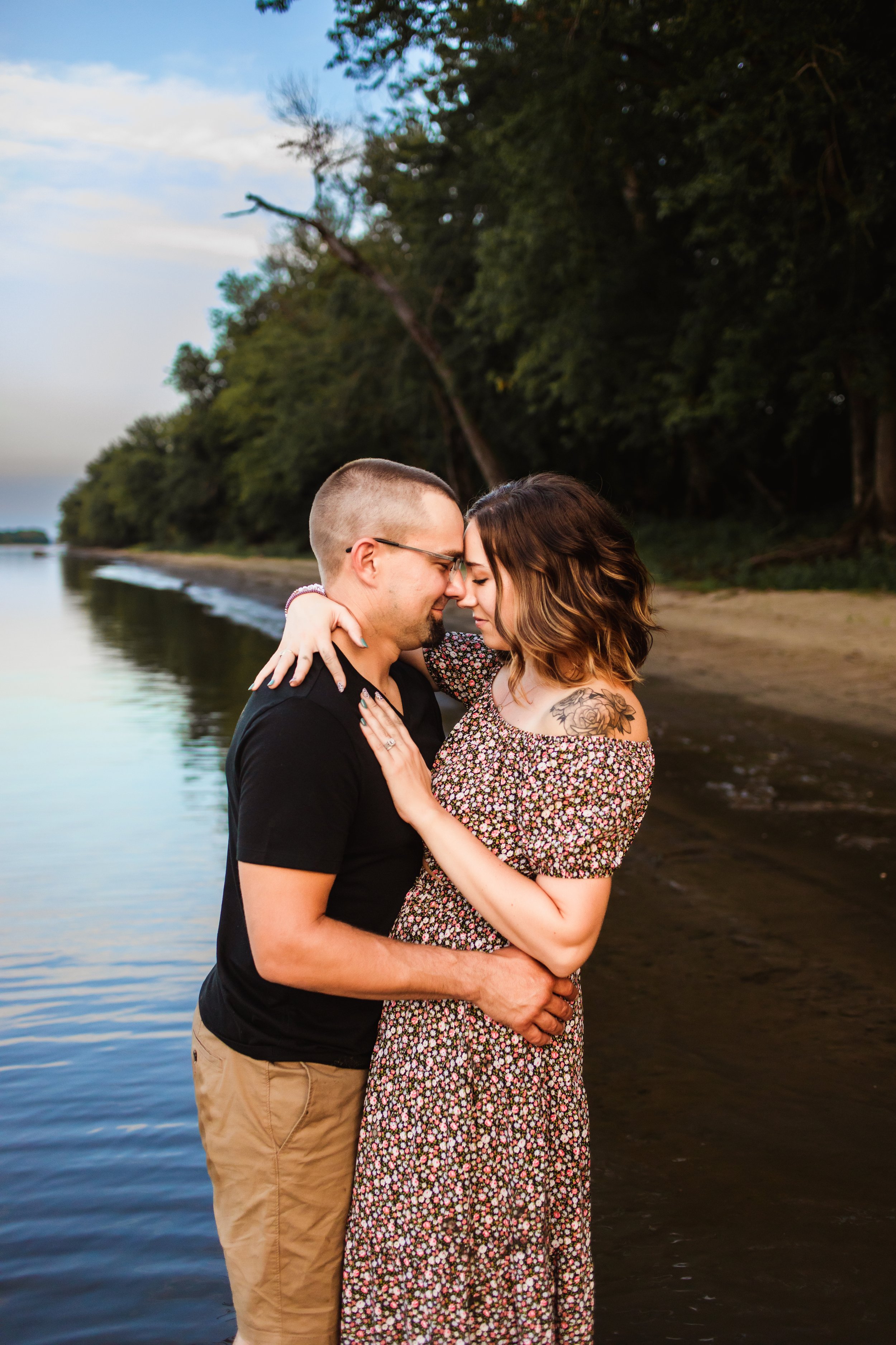  A husband and wife embrace while standing in the Illinois River at dusk by Teala Ward Photography. Couple in love portrait #TealaWardPhotography #TealaWardFamilies #IllinoisRiverPhotography #IllinoisFamilyPhotography #familylifestylepics 