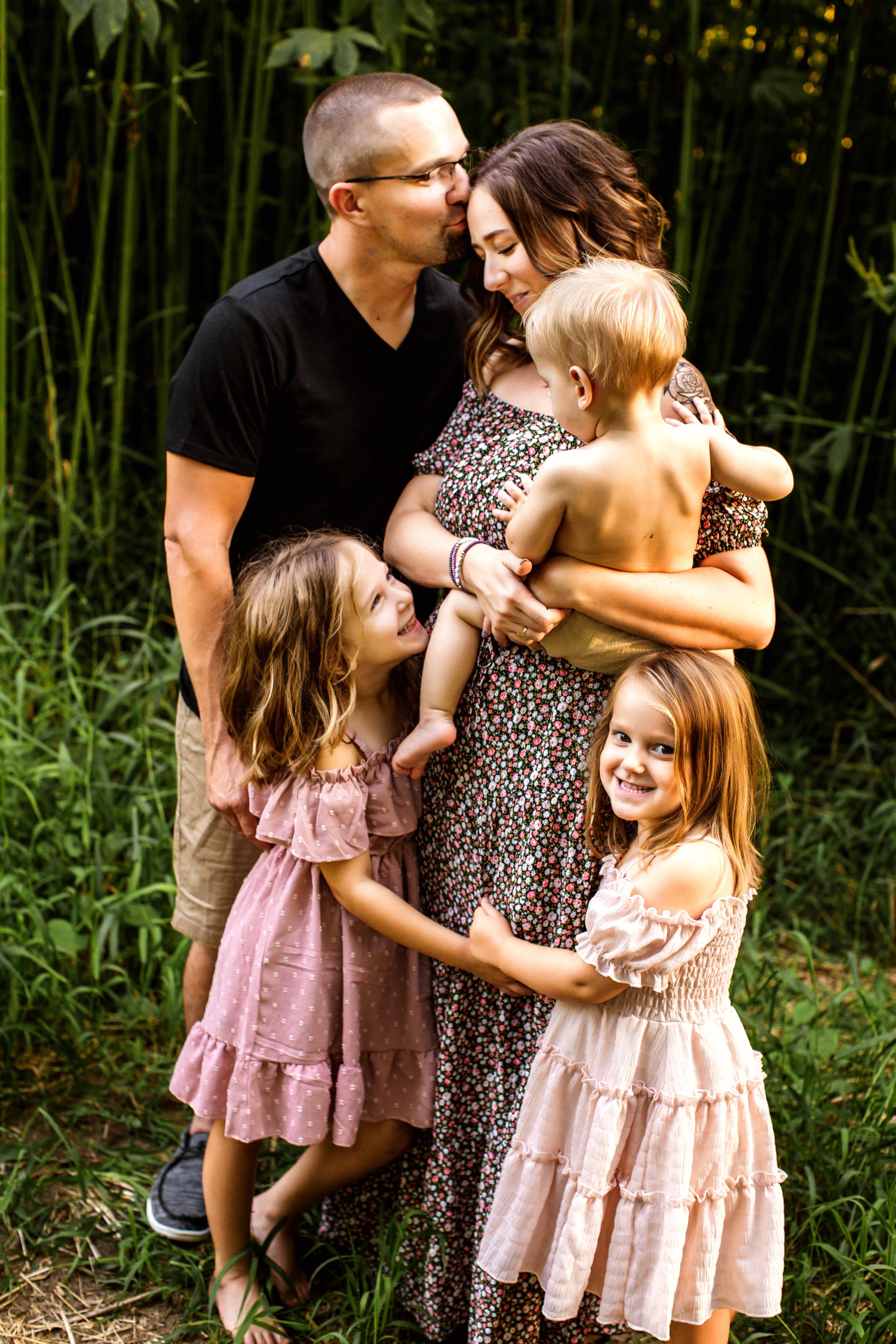  A father kisses his wife's forehead as the kids snuggle around them in the Illinois Valley by Teala Ward Photography. family portraits #TealaWardPhotography #TealaWardFamilies #IllinoisRiverPhotography #IllinoisFamilyPhotography #familylifestylepics