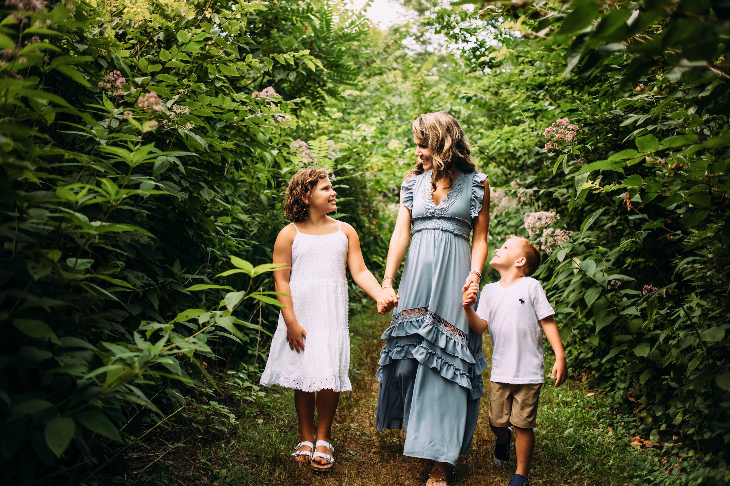  A mother holds her children's hands while walking through a green forest alcove by Teala Ward Photography. Illinois family moments #motherhood #mommapics #TealaWardPhotography #TealaWardFamilies #IllinoisPhotographers #IllinoisFamilyPhotography 
