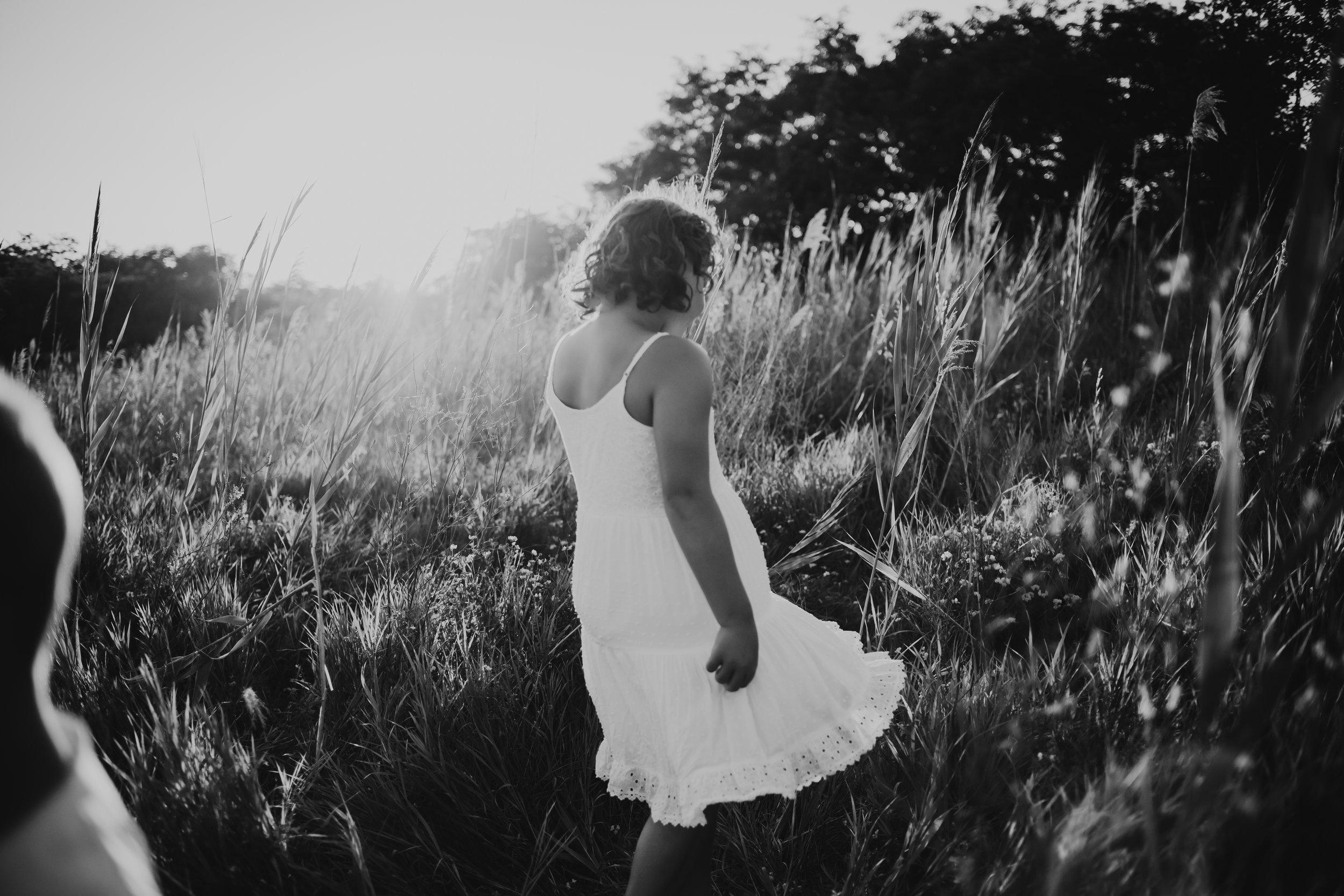  A little girl dances in green grass in the Illinois Valley by Teala Ward Photography. black and white portraits #motherhood #mommapics #TealaWardPhotography #TealaWardFamilies #IllinoisPhotographers #IllinoisFamilyPhotography 