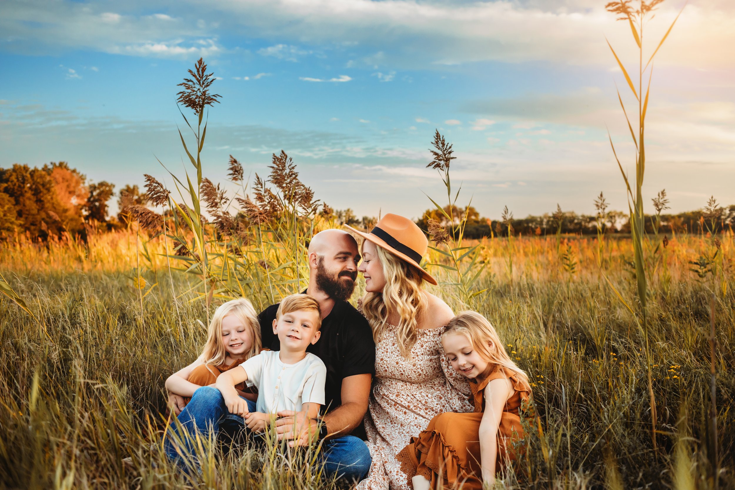  A family is sitting in a yellow grass field in Illinois captured by Teala Ward Photography. stunning midwest family portraits #TealaWardPhotography #IllinoisValleyPhotographer #midwestphotography #TealaWardFamilies #Illinoisfamilypictures 