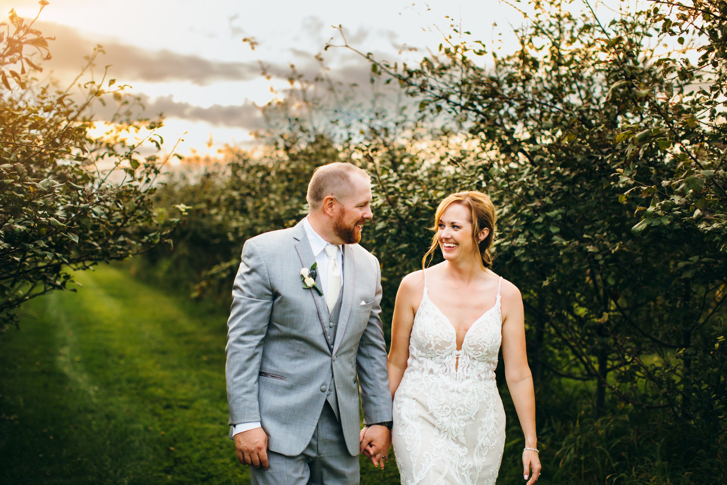  Bride and groom walking in an orchard at sunset by Teala Ward Photography. dynamic wedding shots sunset wedding gray suit summer wedding #TealaWardPhotography #IllinoisValleyPhotographer #summerwedding #TealaWardWeddings #Illinoisweddings  