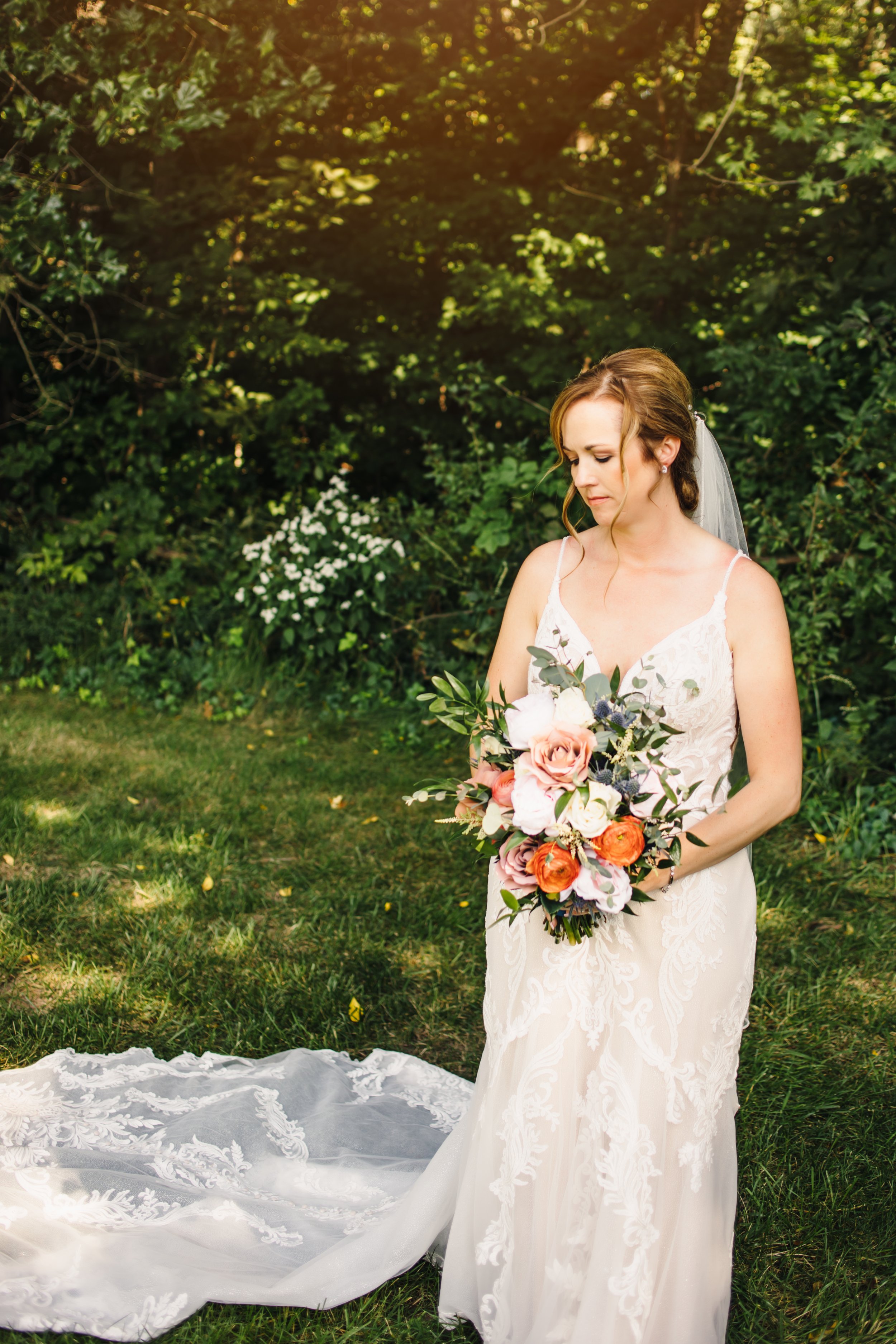  A bride in a spaghetti strap lace wedding gown with a white and orange summer bouquet by Teala Ward Photography. bridals Illinois Valley #TealaWardPhotography #IllinoisValleyPhotographer #summerwedding #TealaWardWeddings #Illinoisweddings  
