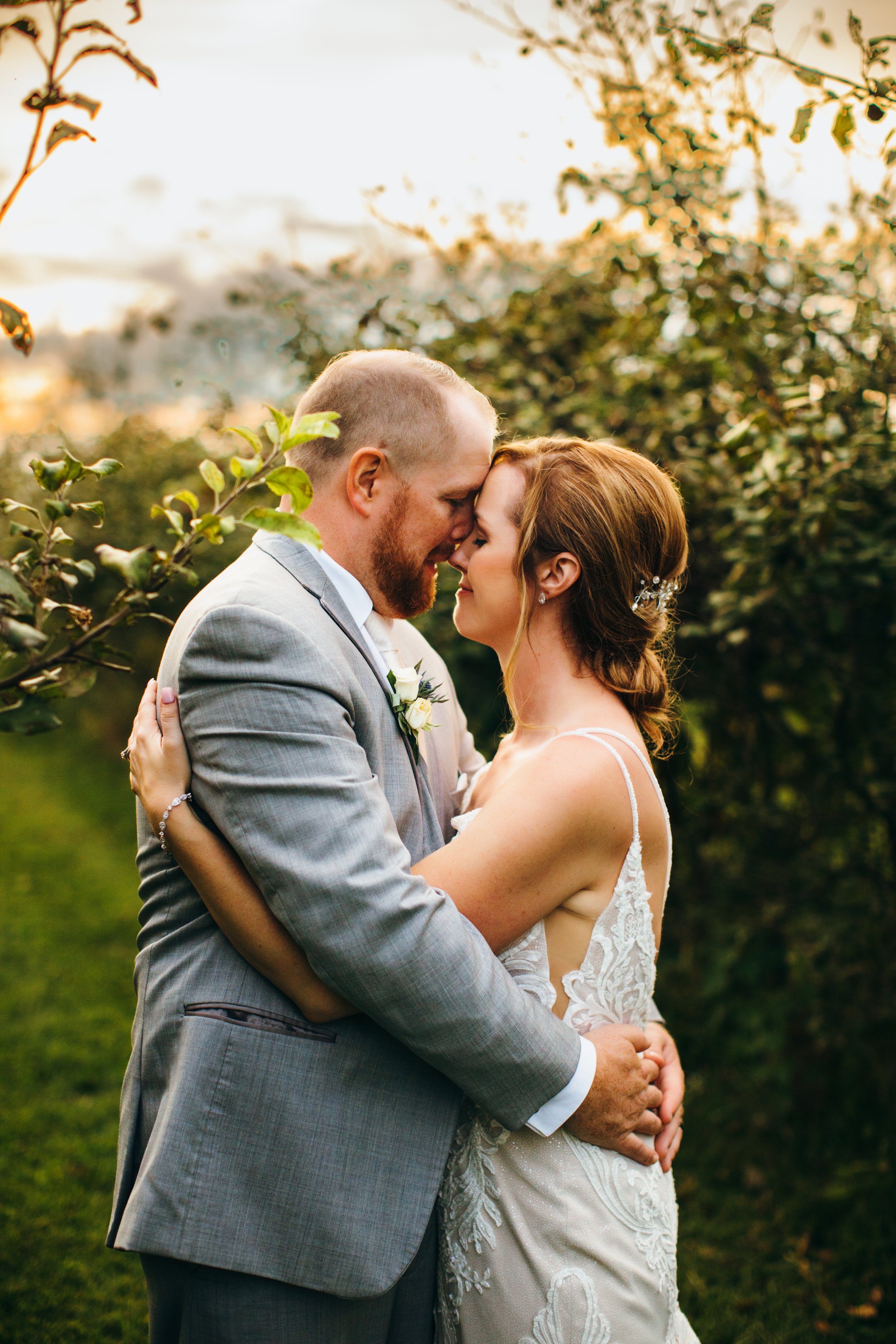  Teala Ward Photography a wedding photographer in the Illinois Valley captures a bride and groom hugging at sunset in an orchard. sunset bridals #TealaWardPhotography #IllinoisValleyPhotographer #summerwedding #TealaWardWeddings #Illinoisweddings  