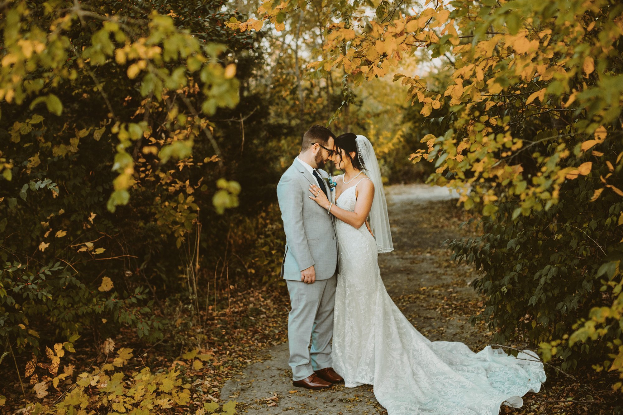  The bride snuggles into the groom’s embrace under an archway of fall leaves by Teala Ward Photography. wedding photos #TealaWardPhotography #TealaWardWeddings #WeddingLocationsIllinois #IllinoisWedding #weddingdetails #weddingphotography #married 