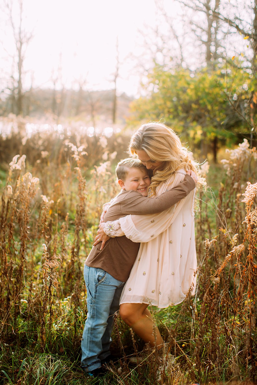 A mother hugs her blonde elementary-age son at dusk in Illinois by Teala Ward Photography. midwest family photography #TealaWardPhotography #TealaWardFamilies #holidayfamilypics #photography #Illinoisfamilyphotography #familysession 