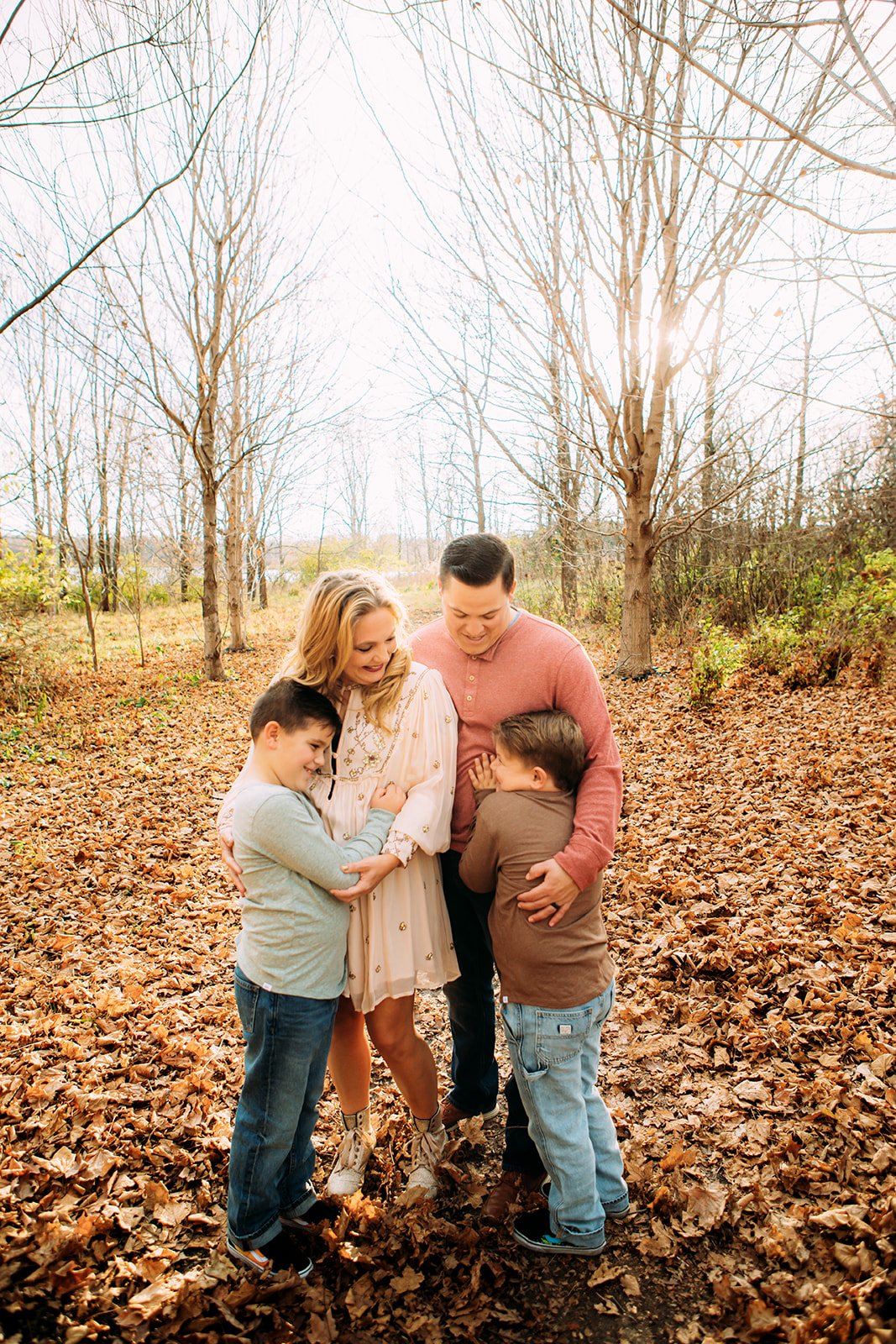  During the fall in the midwest, Teala Ward Photography captures a mother and father hugging their sons. family hug candid family photo #TealaWardPhotography #TealaWardFamilies #holidayfamilypics #photography #Illinoisfamilyphotography #familysession