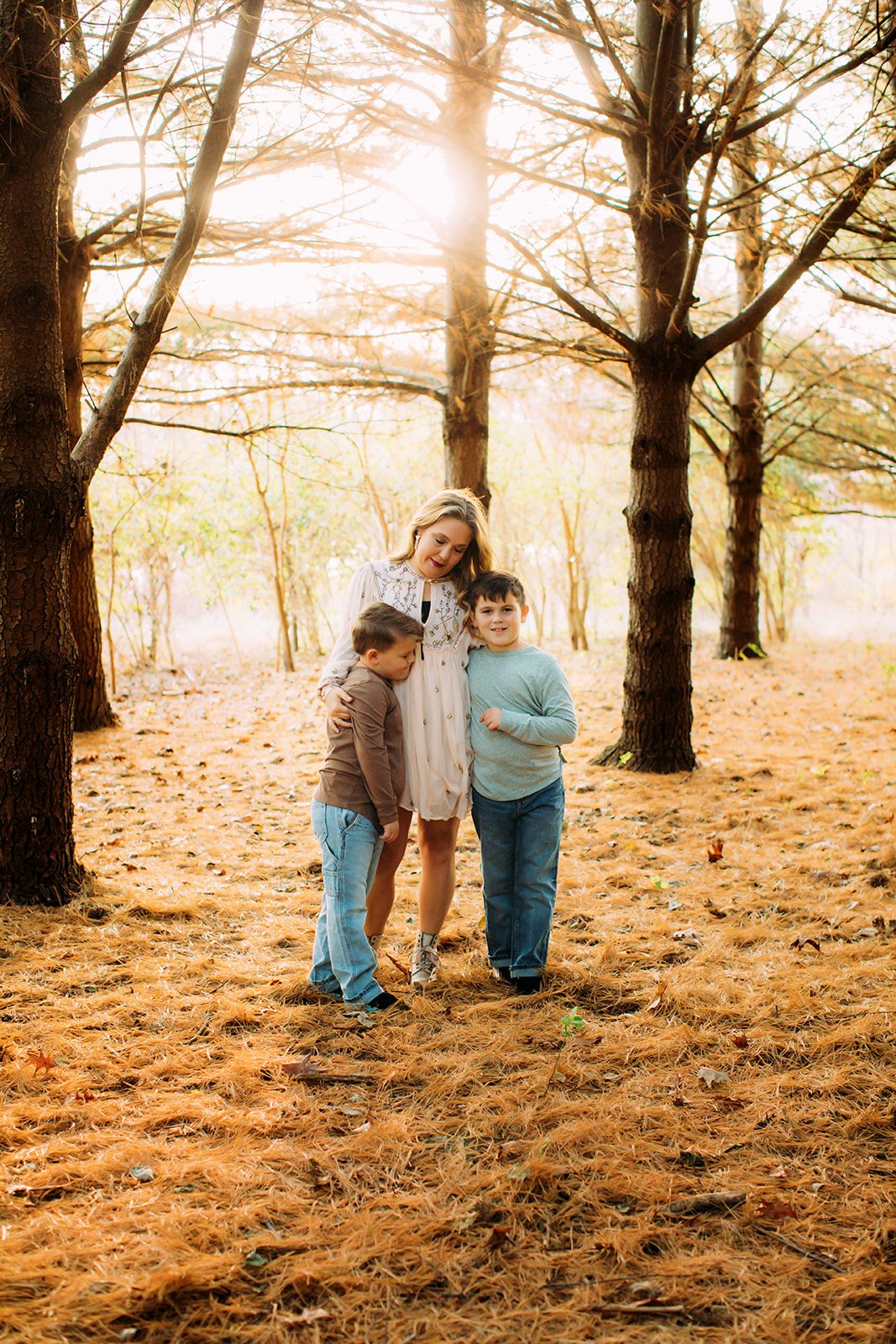  In a forest with warm sunlight and a mossy floor, a mother hugs her two boys by Teala Ward Photography.  mossy forest floor #TealaWardPhotography #TealaWardFamilies #holidayfamilypics #photography #Illinoisfamilyphotography #familysession 