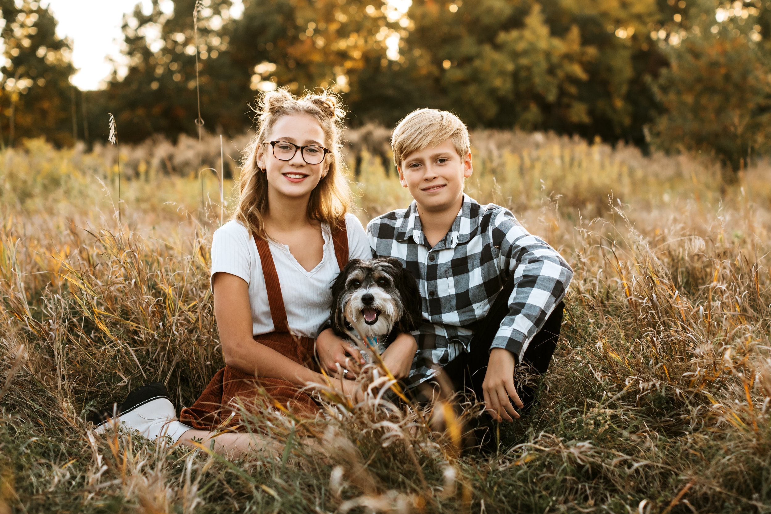  A brother and sister sit with their dog in a yellow grass field by Teala Ward Photography in the IL valley. dog with kids #TealaWardPhotography #TealaWardFamilies #IllinoisValleyfamilypics #fursibiling #Illinoisfamilyphotography #brother&amp;sister 