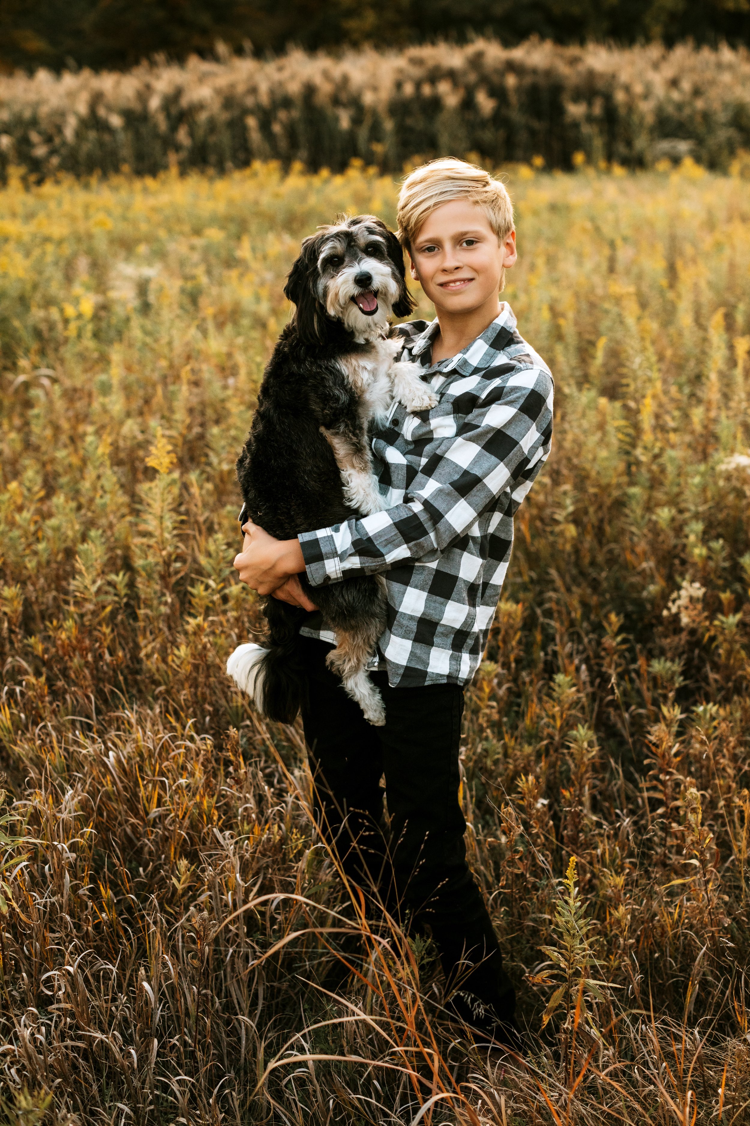  Teala Ward Photography captures a boy holding his beloved dog in a grass field at sunset. boy and dog boys best friend #TealaWardPhotography #TealaWardFamilies #IllinoisValleyfamilypics #fursibiling #Illinoisfamilyphotography #brother&amp;sister 