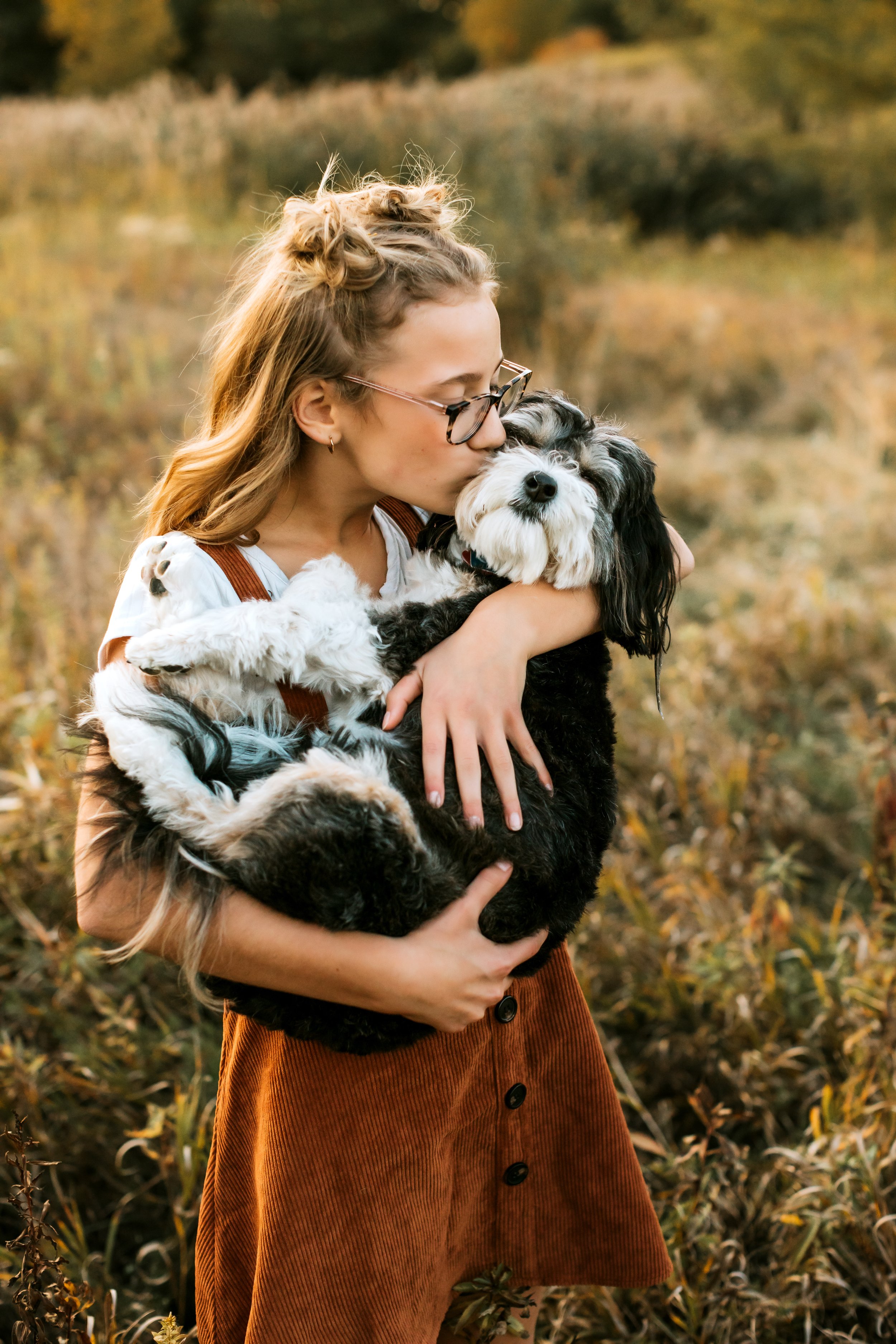  A girl kisses her dog on the cheek while holding him in her arms by Teala Ward Photography. girl style for pics #TealaWardPhotography #TealaWardFamilies #IllinoisValleyfamilypics #fursibiling #Illinoisfamilyphotography #brother&amp;sister 