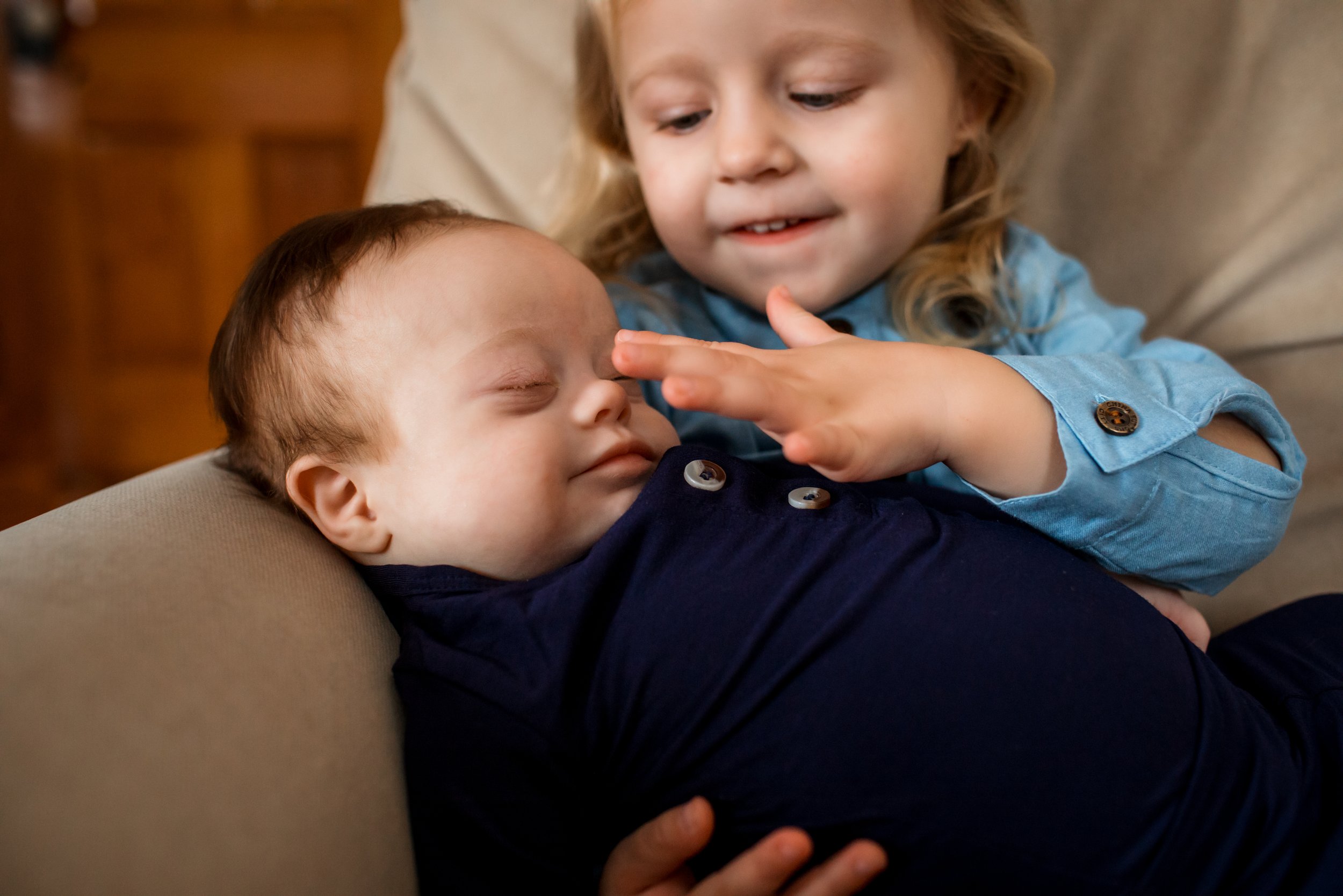  A toddler little girl holds her little brother and touches his nose by Teala Ward Photography. in-home newborns what to know #TealaWardPhotography #TealaWardNewborns #InHomeNewborns #IllinoisPhotographer #ILNewborns #IllinoisValleyNewborns 