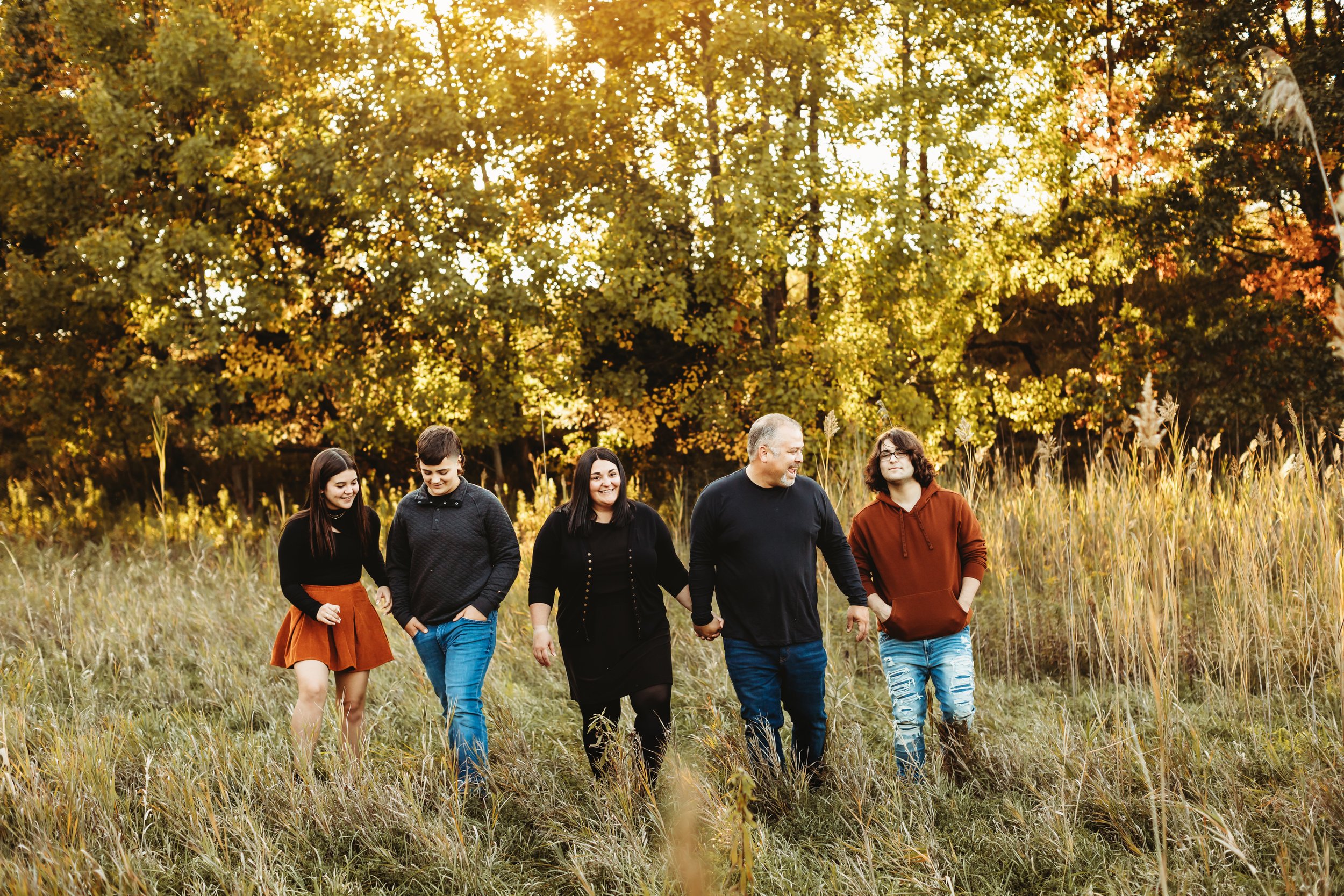  A family of five walks through tall yellow grass in Buffalo Rock, Illinois with Teala Ward Photography at sunset. family portraits with warm lighting and green trees #TealaWardPhotography #TealaWardFamilies #Outdoorfamilyportraits #IllinoisPhotograp