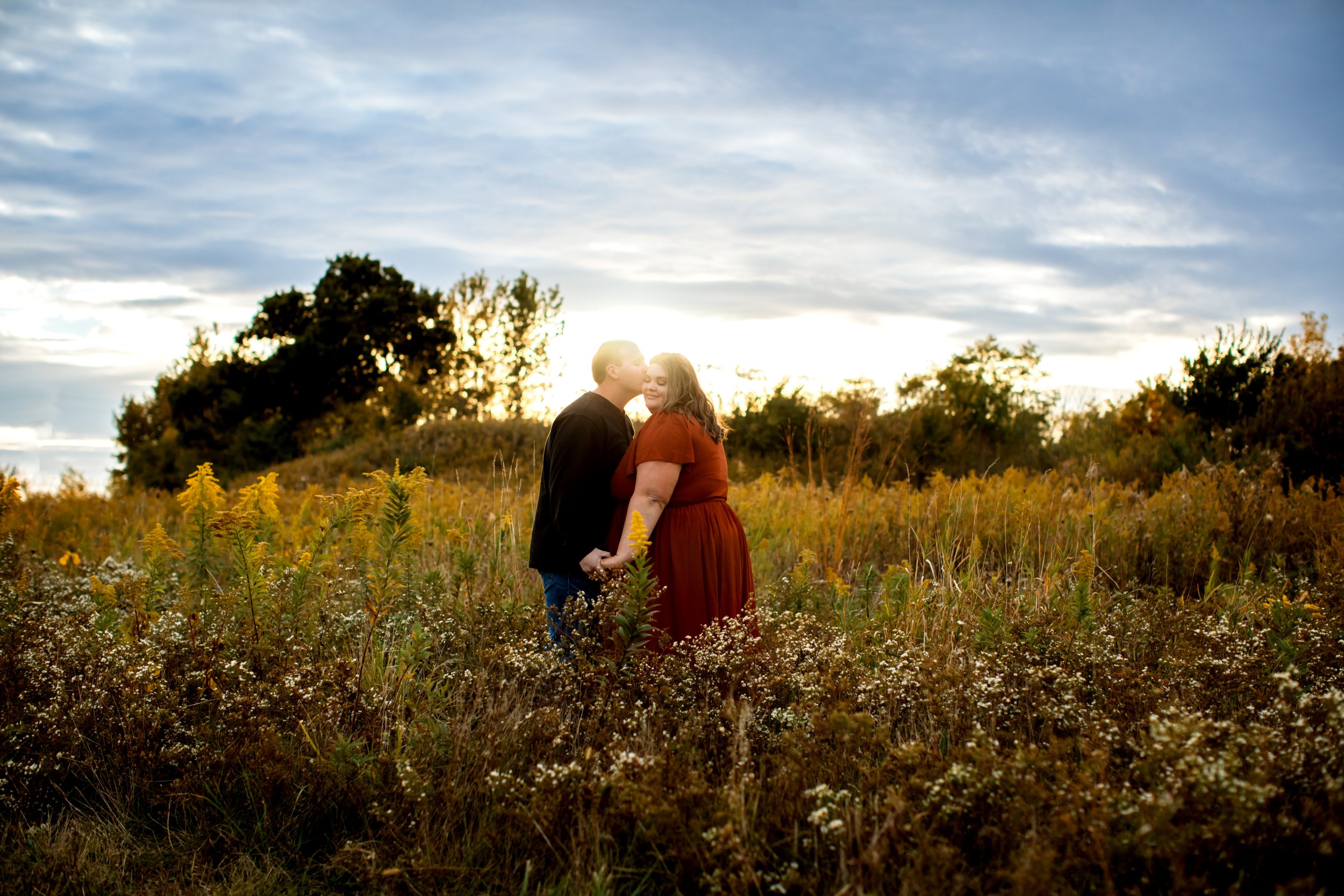  A groom kisses his soon-to-be-bride in a field with yellow flowers with the sun behind them by Teala Ward Photography. engagements find the right photographer #TealaWardPhotography #TealaWardEngagements #Weddingphotographer #ILweddings #Weddingengag