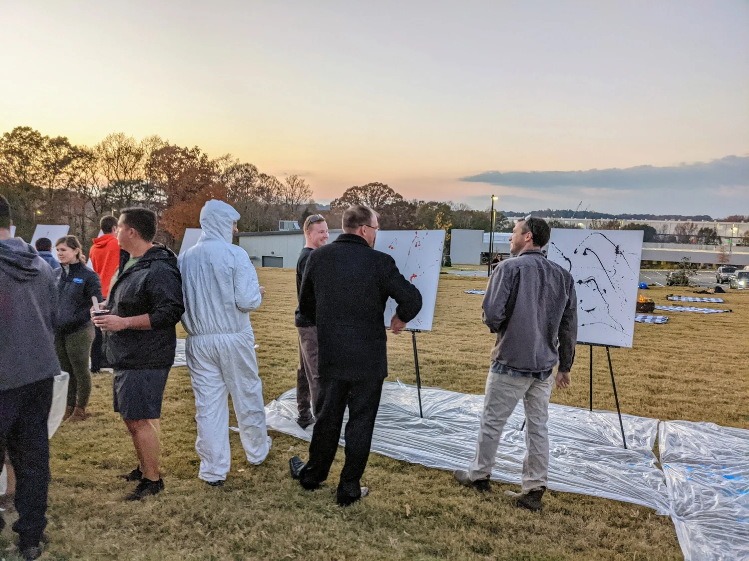 Suits and coveralls, canvases on easels, company offsite.