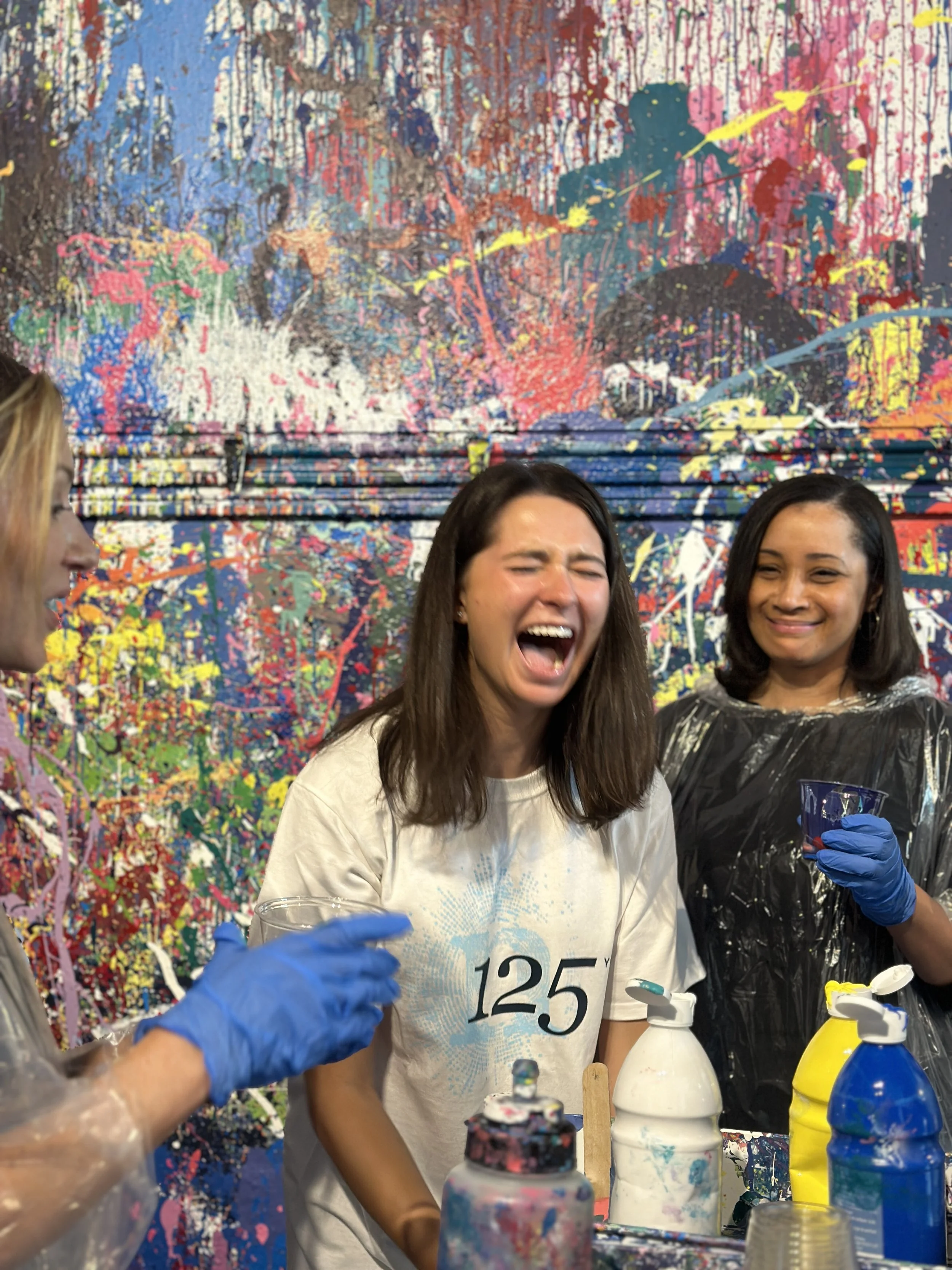 Woman having fun time splatter painting in an art studio, mixing paint colors.
