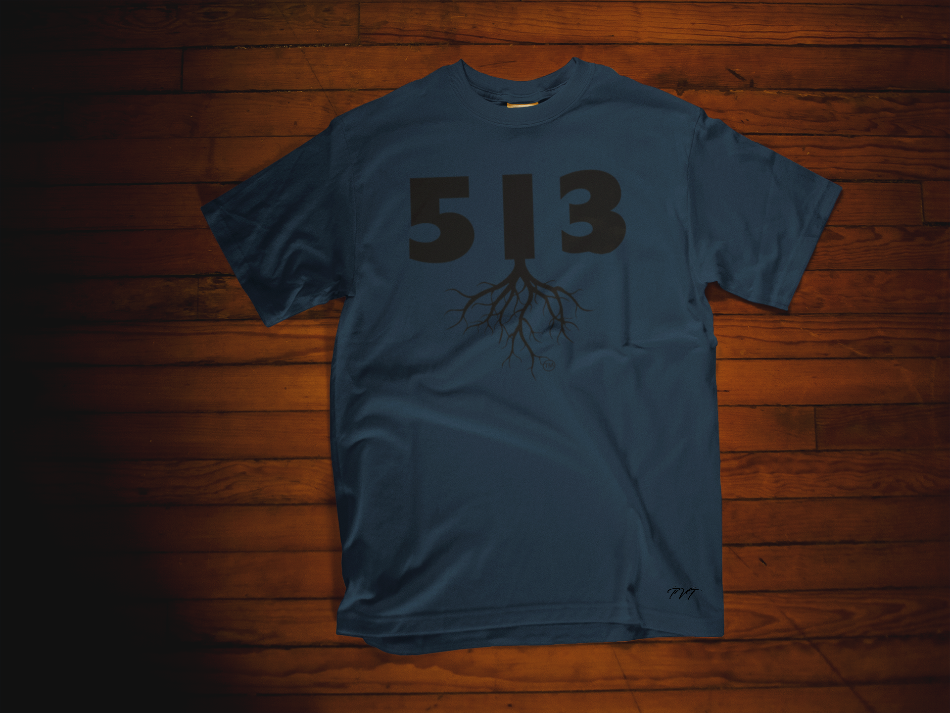 T-SHIRT MOCKUP OF A 513 AREA CODE NAVY BLUE (BLACK) T-SHIRT LYING OVER A WOODEN SURFACE.png