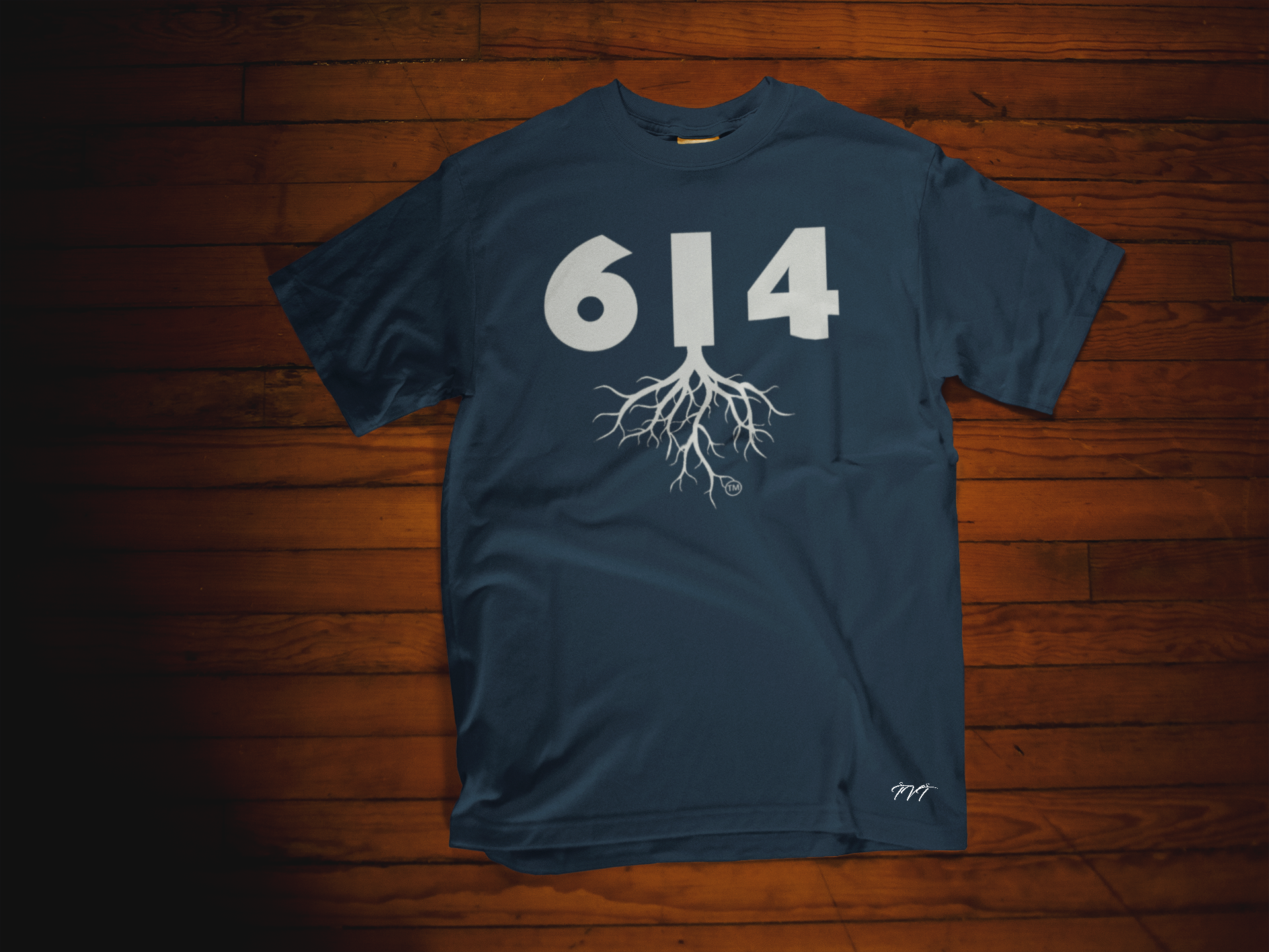 T-SHIRT MOCKUP OF A 614 AREA CODE NAVY BLUE (WHITE) T-SHIRT LYING OVER A WOODEN SURFACE.png