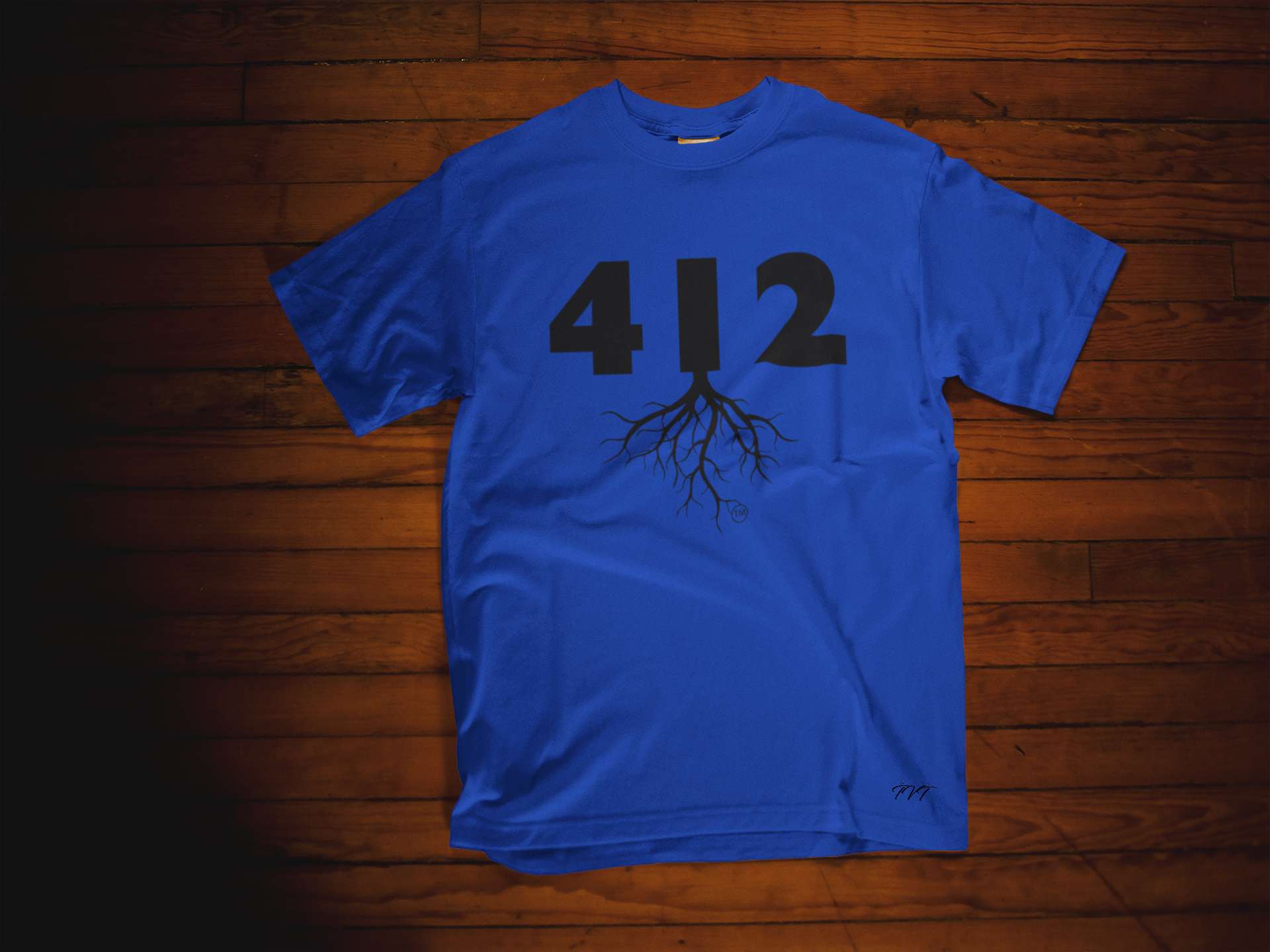 T-SHIRT MOCKUP OF A 412 AREA CODE ROYAL BLUE (BLACK) T-SHIRT LYING OVER A WOODEN SURFACE.png