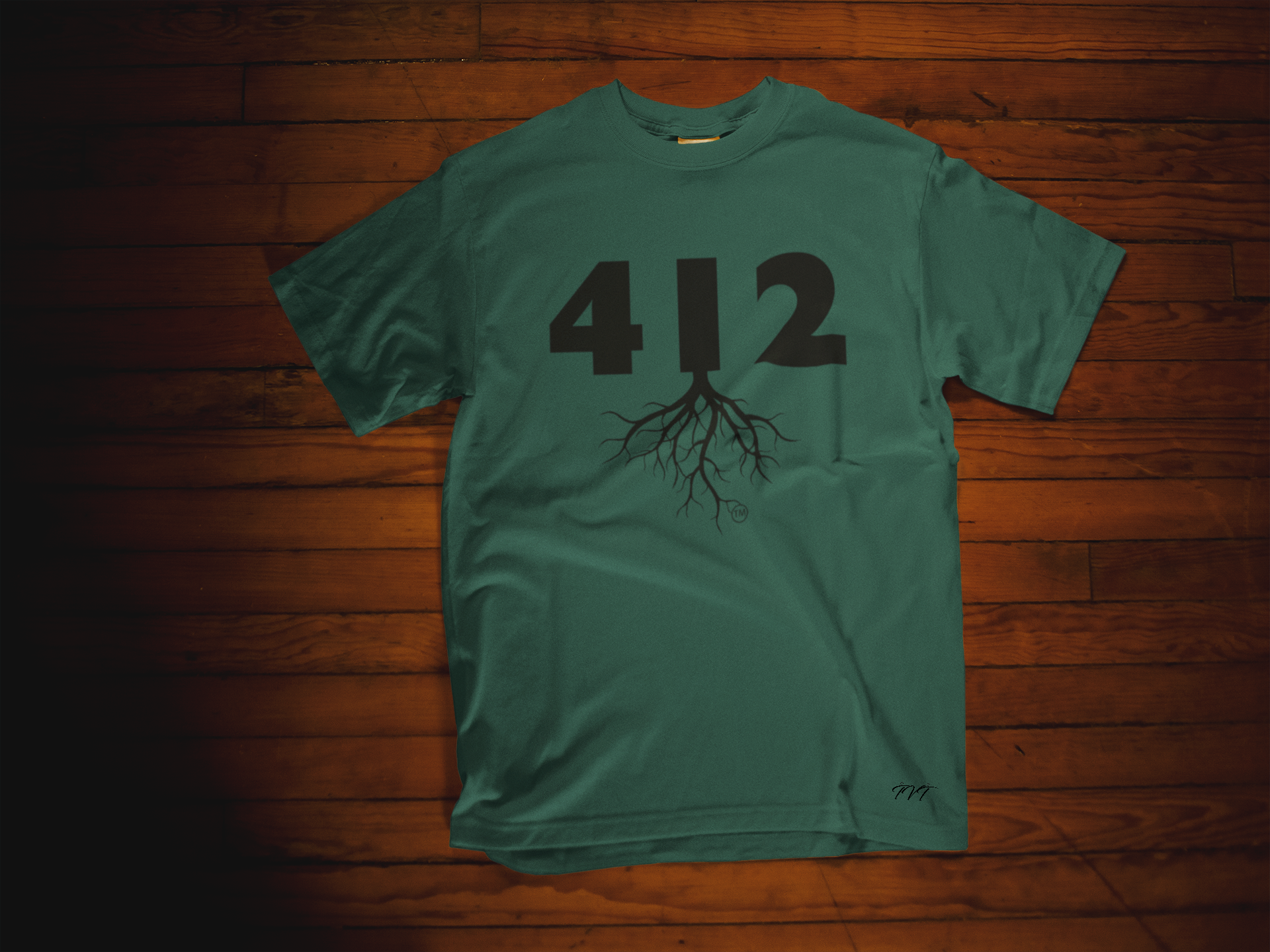 T-SHIRT MOCKUP OF A 412 AREA CODE FOREST GREEN (BLACK) T-SHIRT LYING OVER A WOODEN SURFACE.png