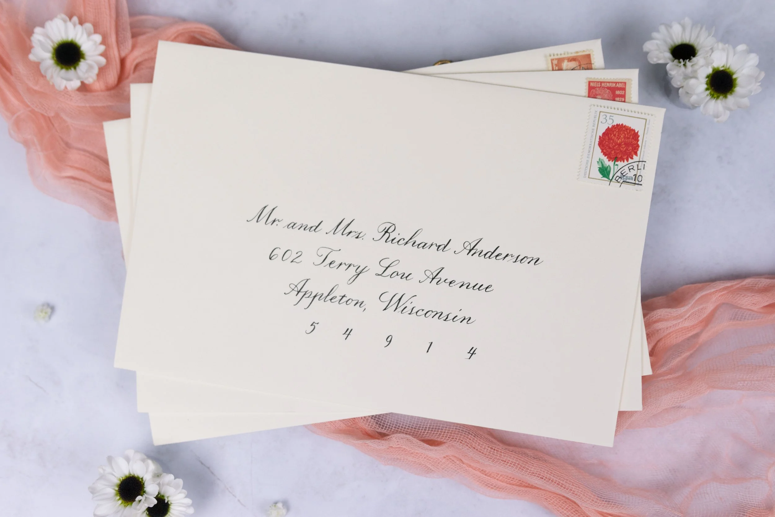 Envelopes address in copperplate. This script style is a favorite for formal events. This particular example has minimal flourishes, but the style can include more depending on your audience and brand. 