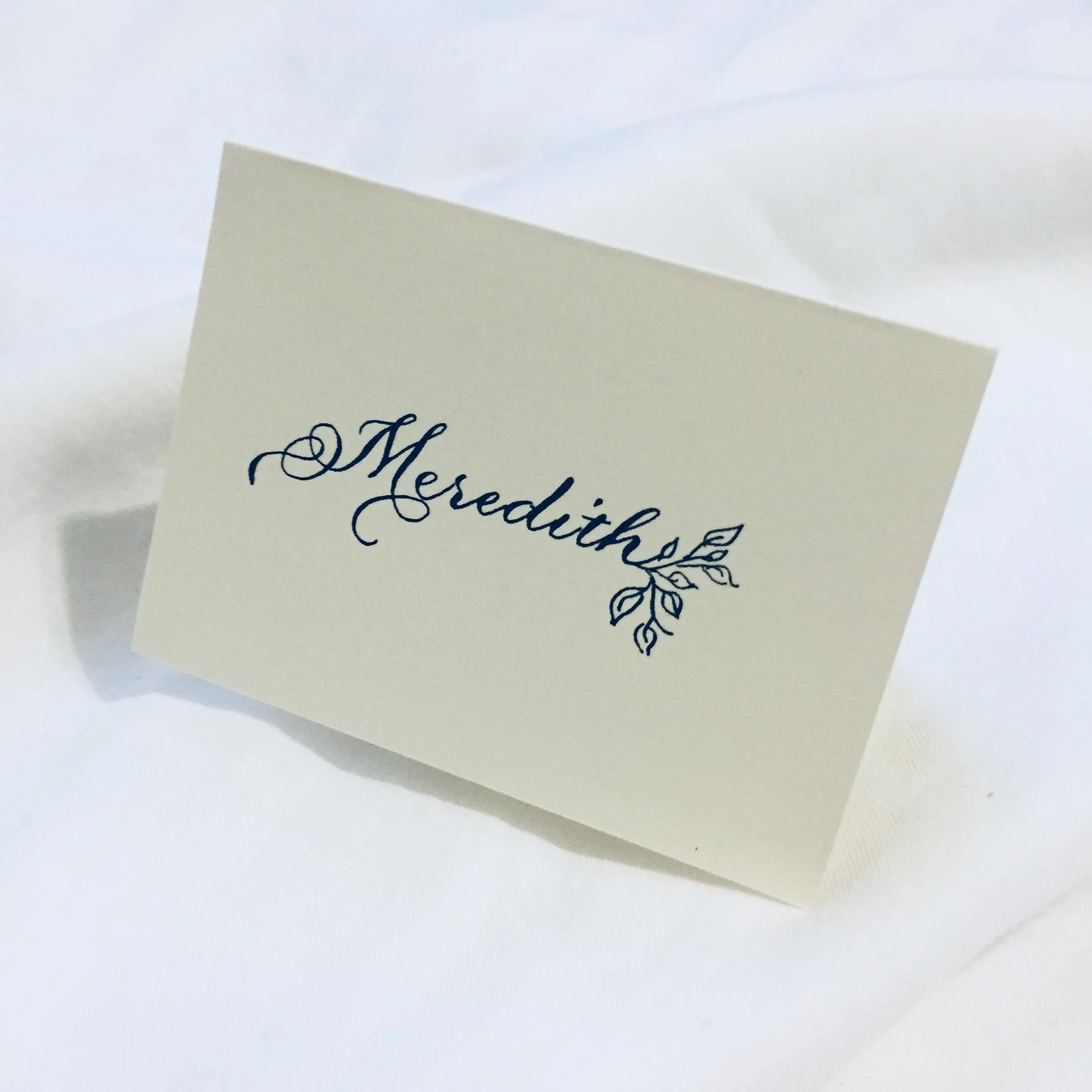 Place card in flourished script with leaves. The right embellishment can elevate the experience guests receive when they see their name. 