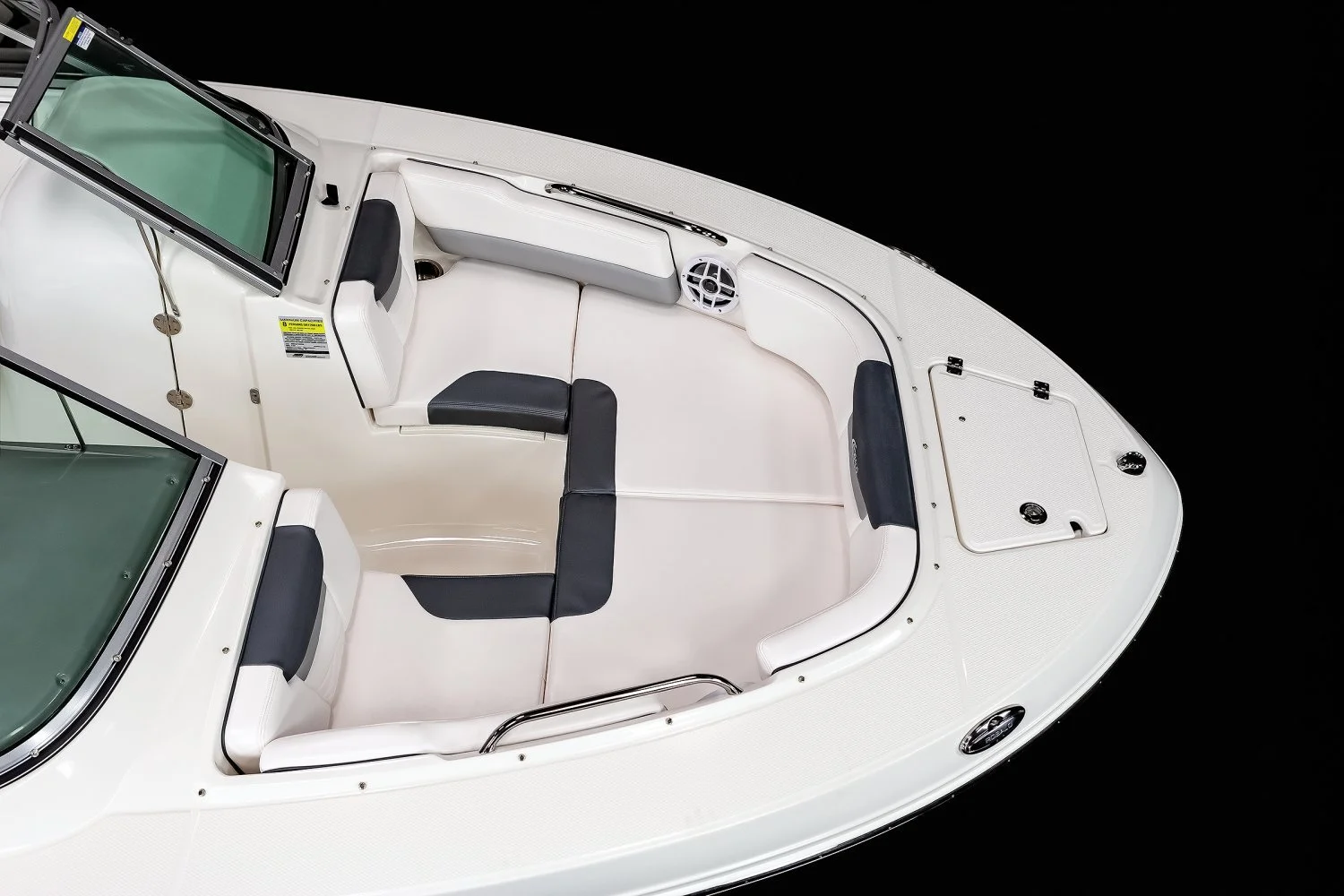 Top view of the bow of a white motorboat with black cushioned seats, a windshield, and a hatch, set against a black background.