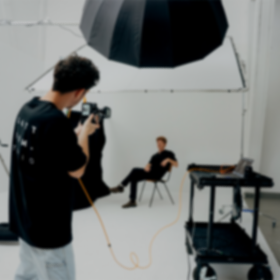 Fotograf macht ein Shooting im Fotostudio mit einem Mann, der auf einem Stuhl sitzt.