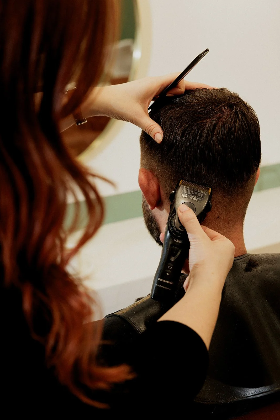 Arielle coupe les cheveux d'un client au poste de coiffage