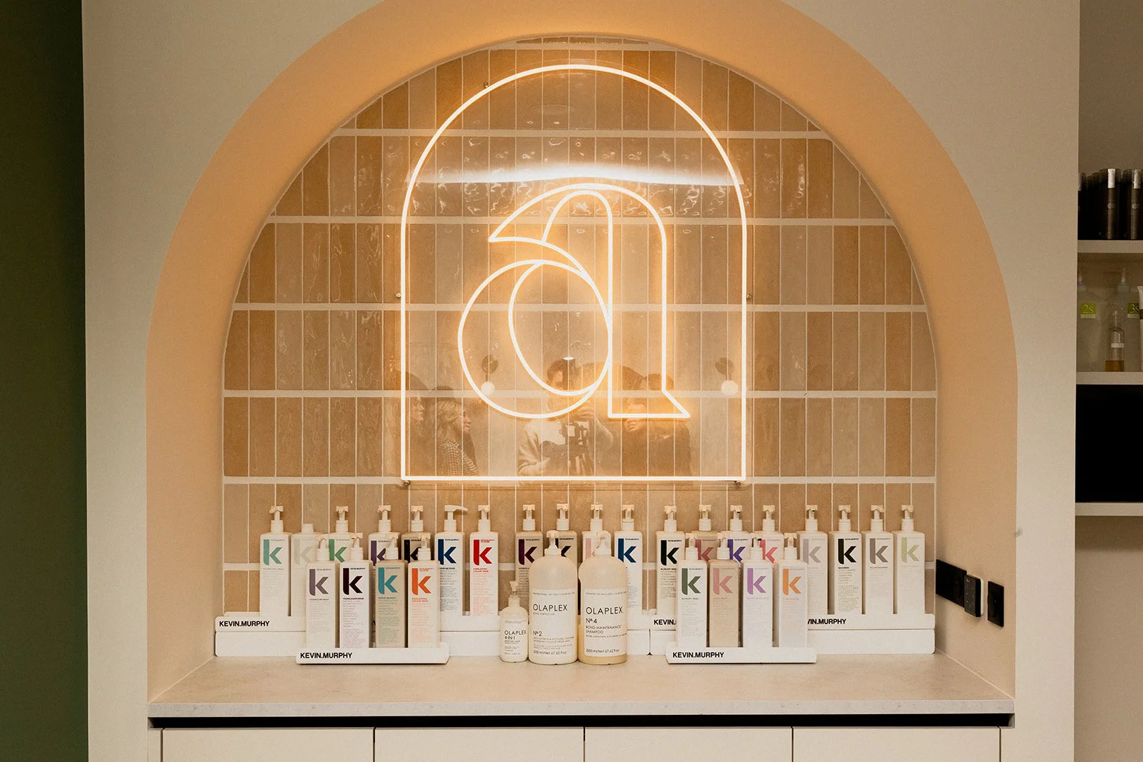 Arche avec un néon avec le "a" du logo Arielle avec une gamme de produits capillaires Olaplex