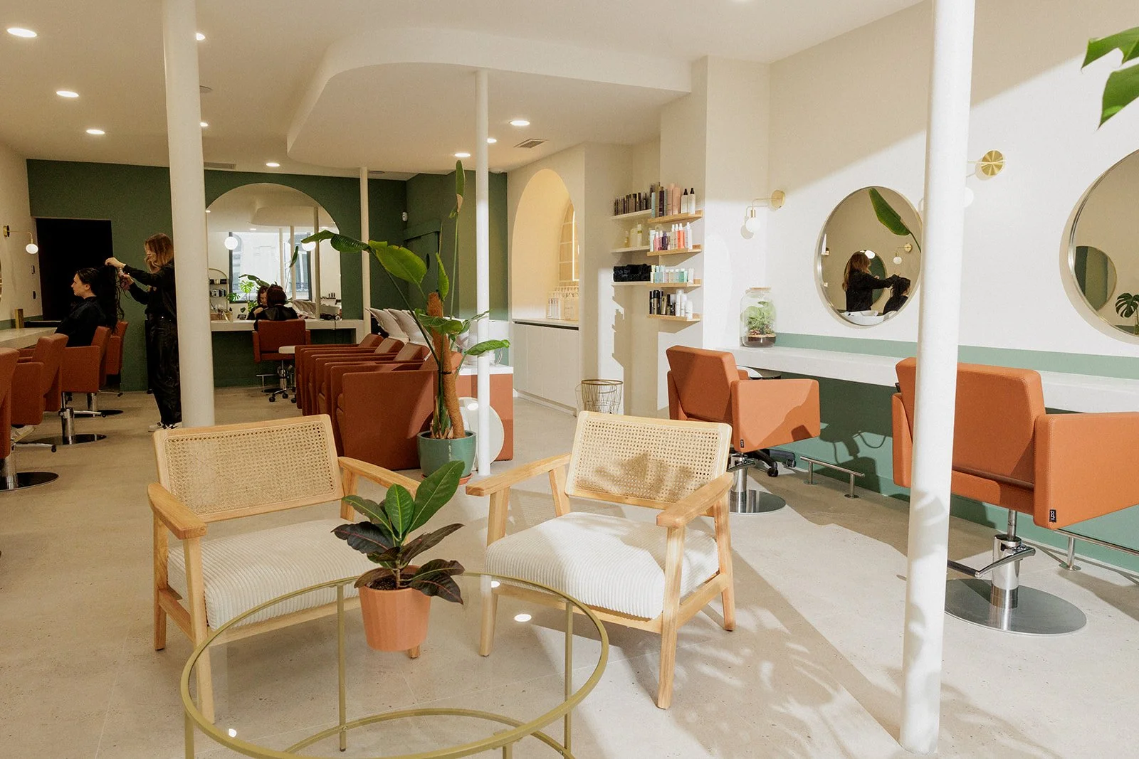 Vue intérieure du salon de coiffure, avec l'espace d'accueil, les postes de coiffage et les bacs de shampoing derrière