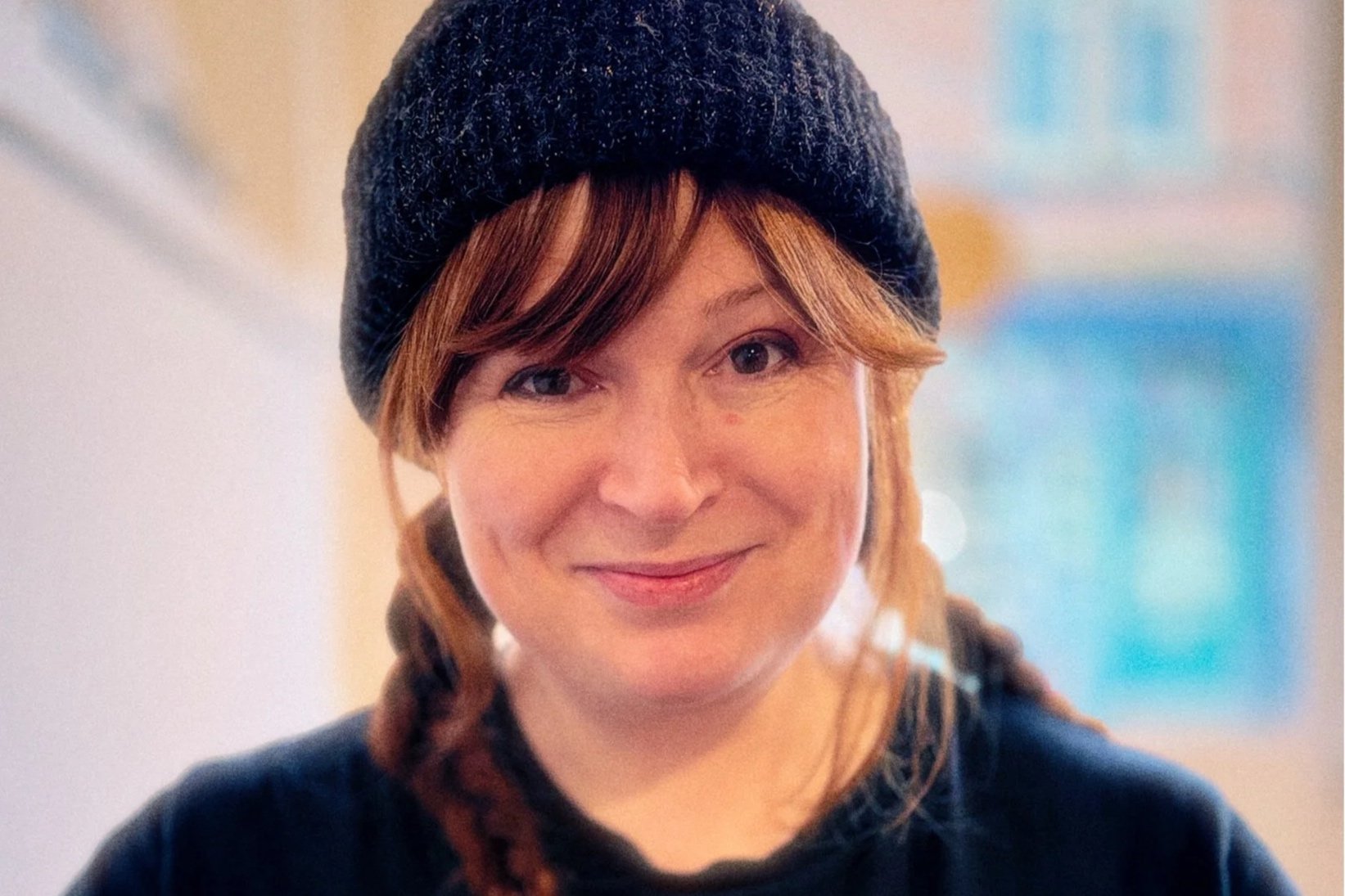 Aoife Glass smiles at the camera. She has plaits and is wearing a black hat