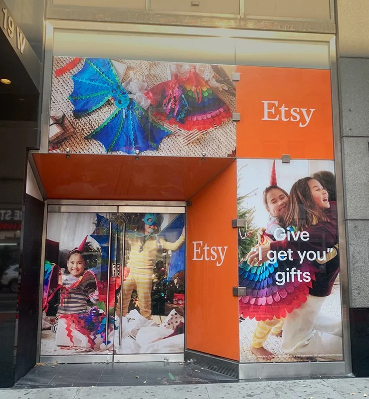 Storefront with advertisements for Etsy, featuring colorful rainbow-themed crafts and children playing while wearing rainbow costumes and accessories.