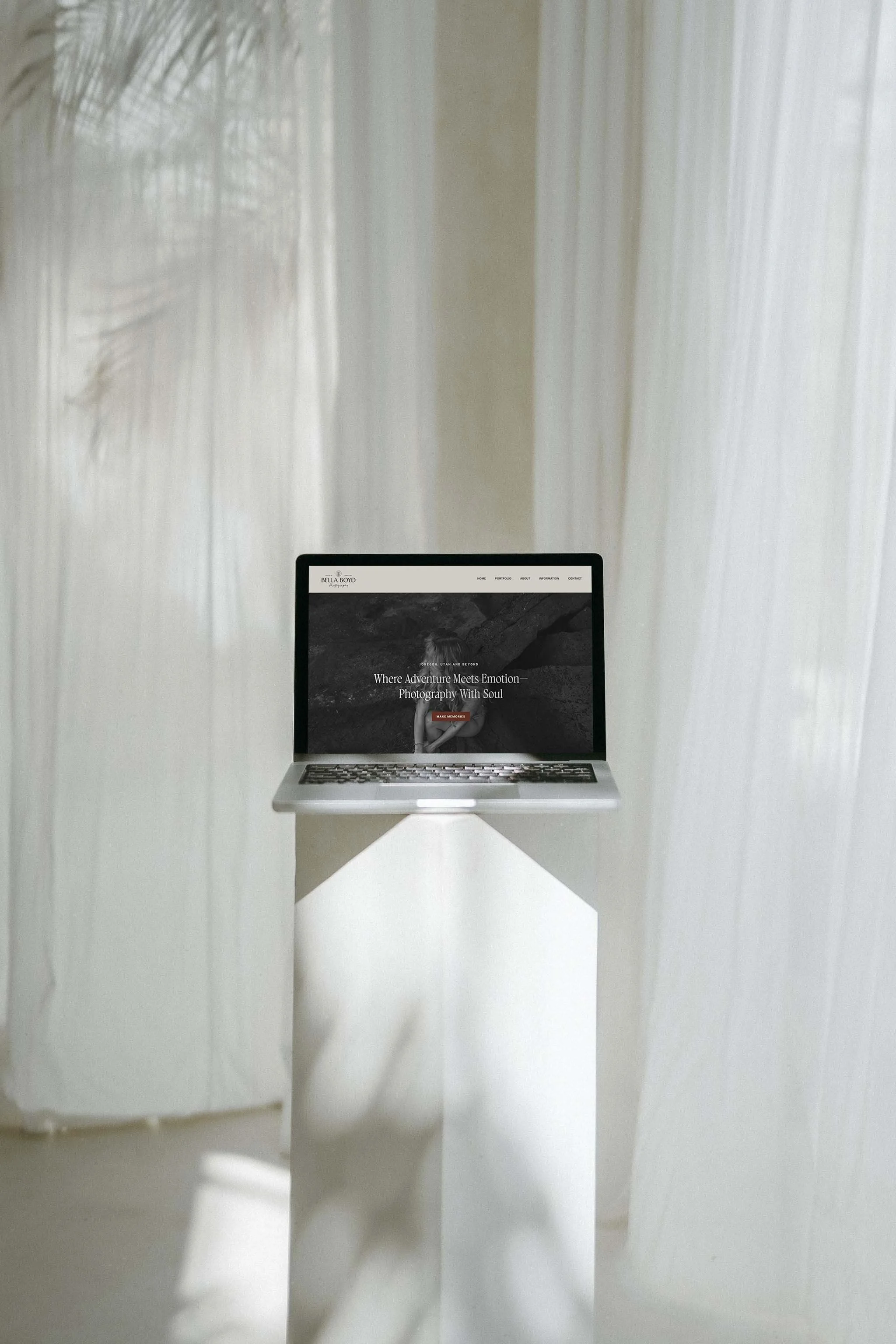 A laptop on a white pedestal displaying a website designed with a custom brand identity by a female entrepreneur in Bend, Oregon. It is in a light, minimalistic room with sheer curtains and natural light.