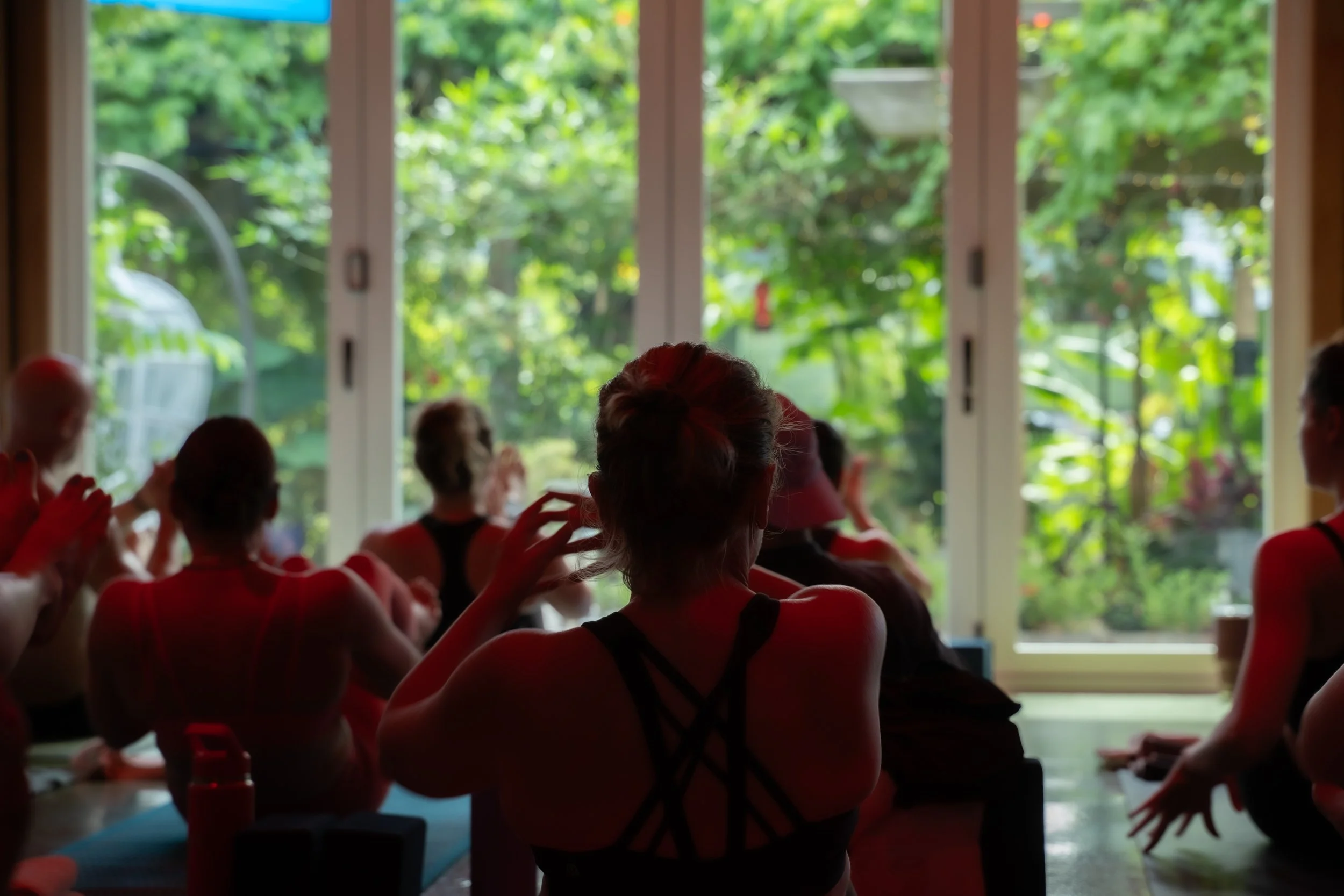 room of yoga students twisting on mats looking out into the garden by photographer Lenee Love