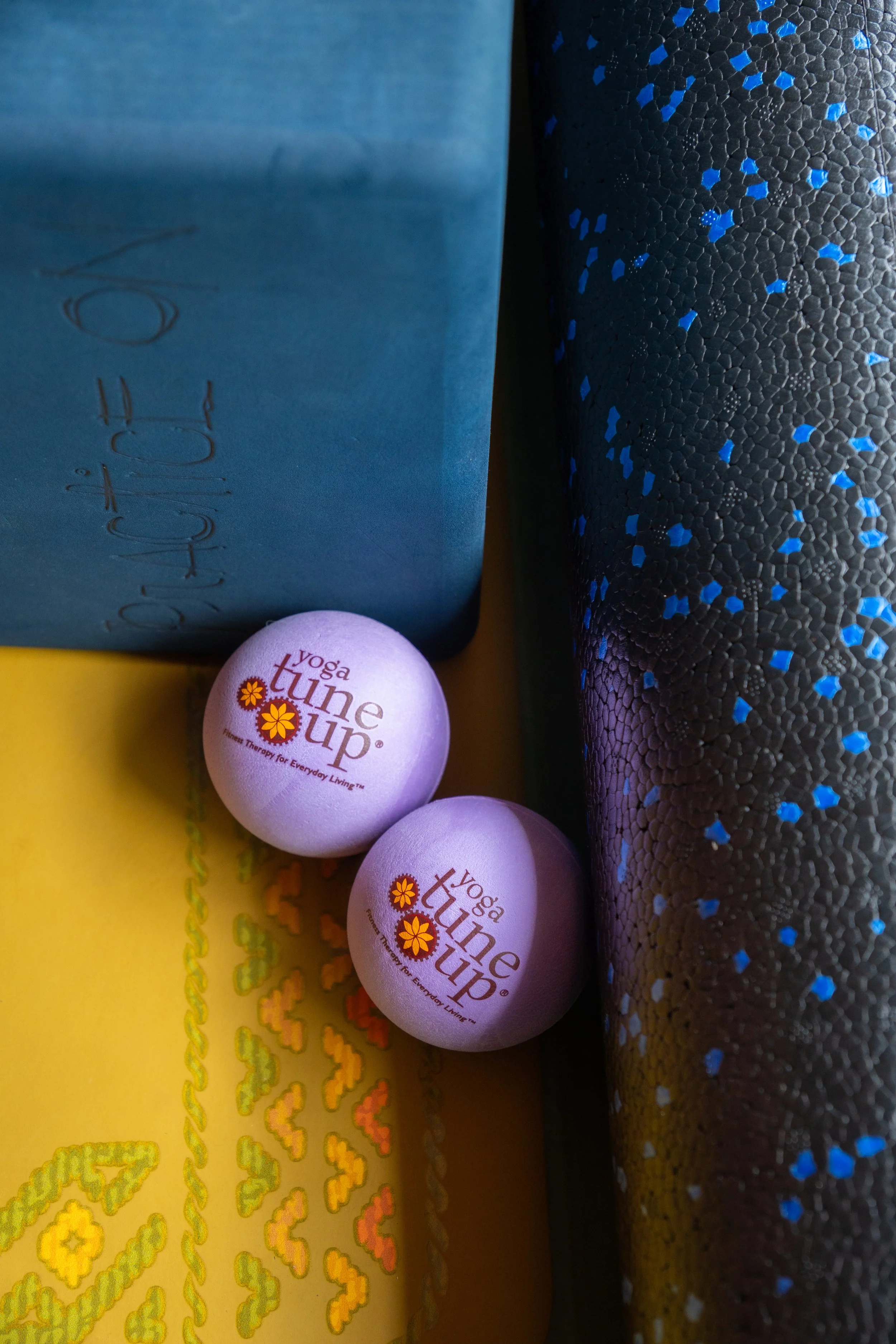 yoga tune up therapy balls on a yellow lifeorme mat next to yoga block and foam roller