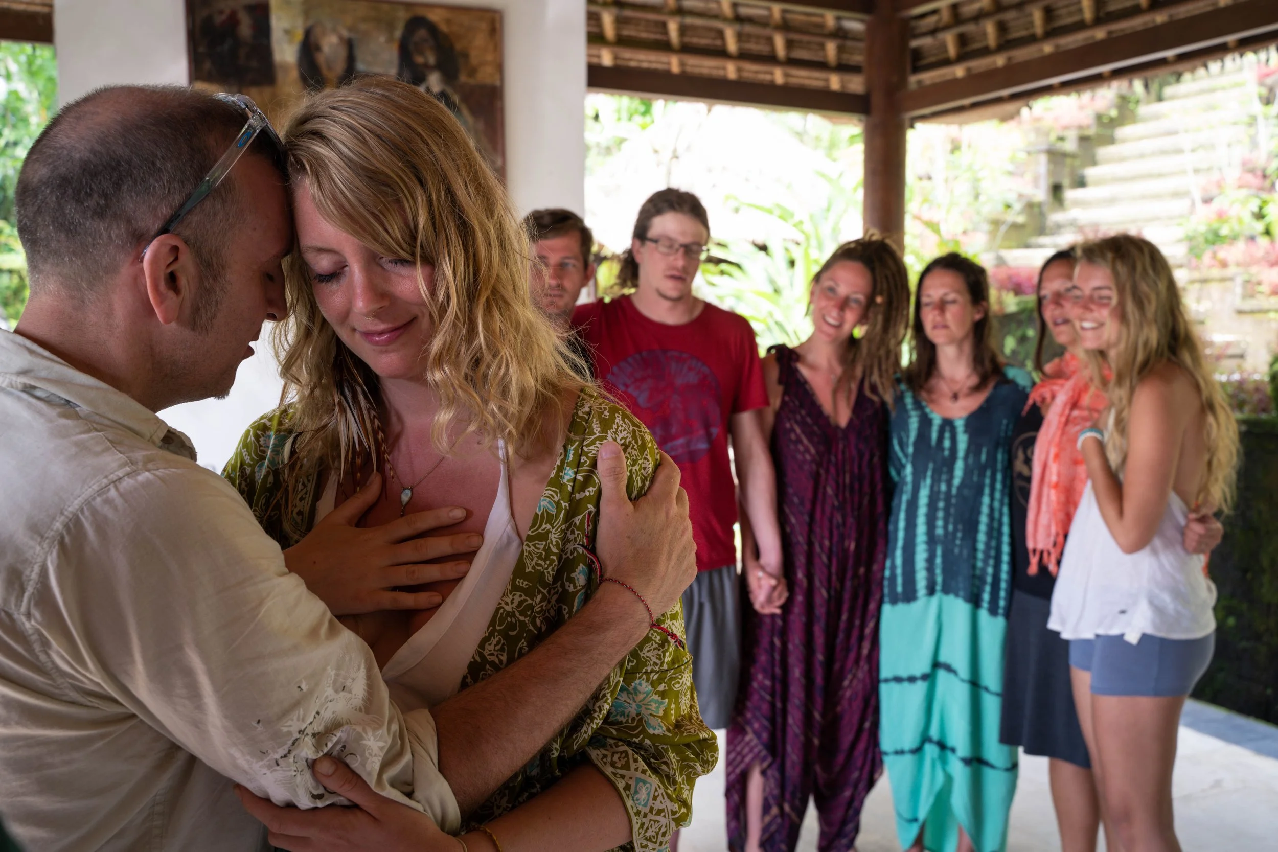 man and woman embracing her hand on her heart in front of a group that's smiling and supporting them at a retreat in Bali by photographer Lenee Love