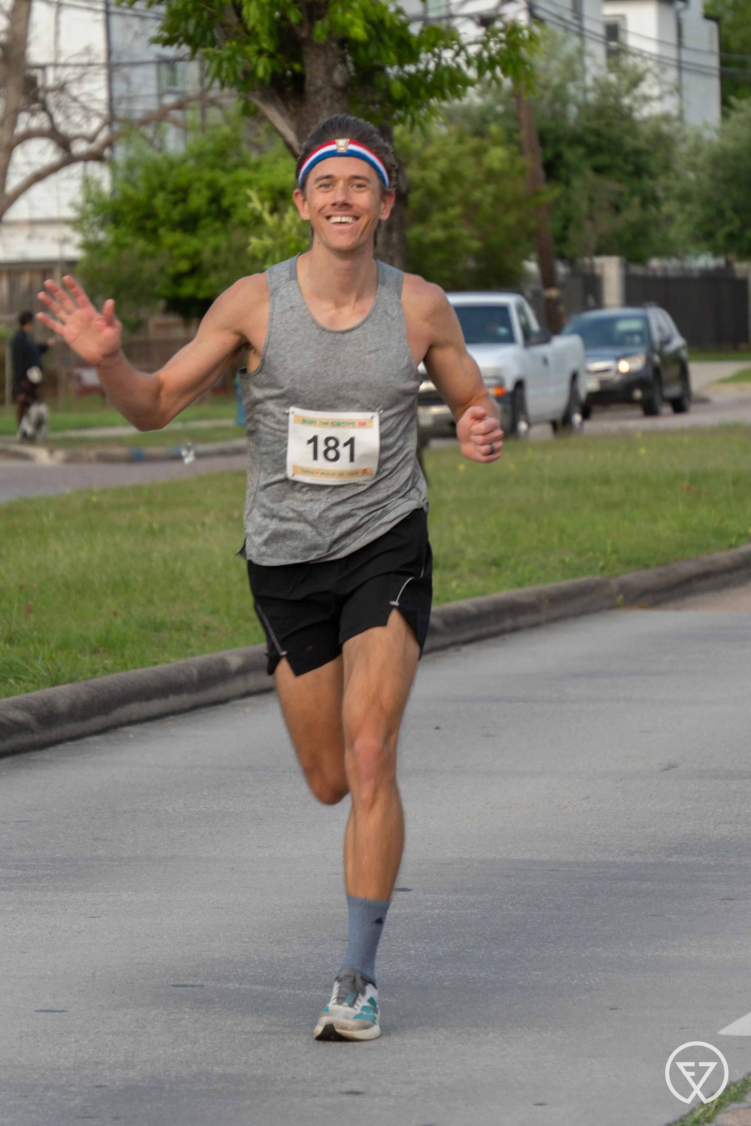 male runner waving to the camera with a smile in a 5k run by photographer Lenee Love