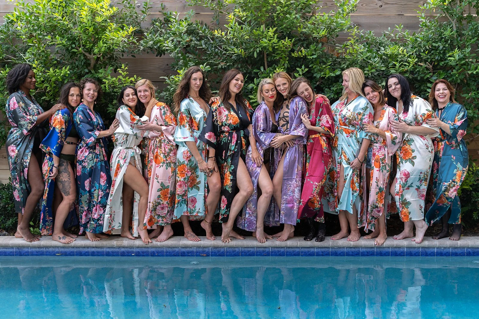 group shot of women by the pool wearing matching satin robes by womens retreat photographer Lenee Love