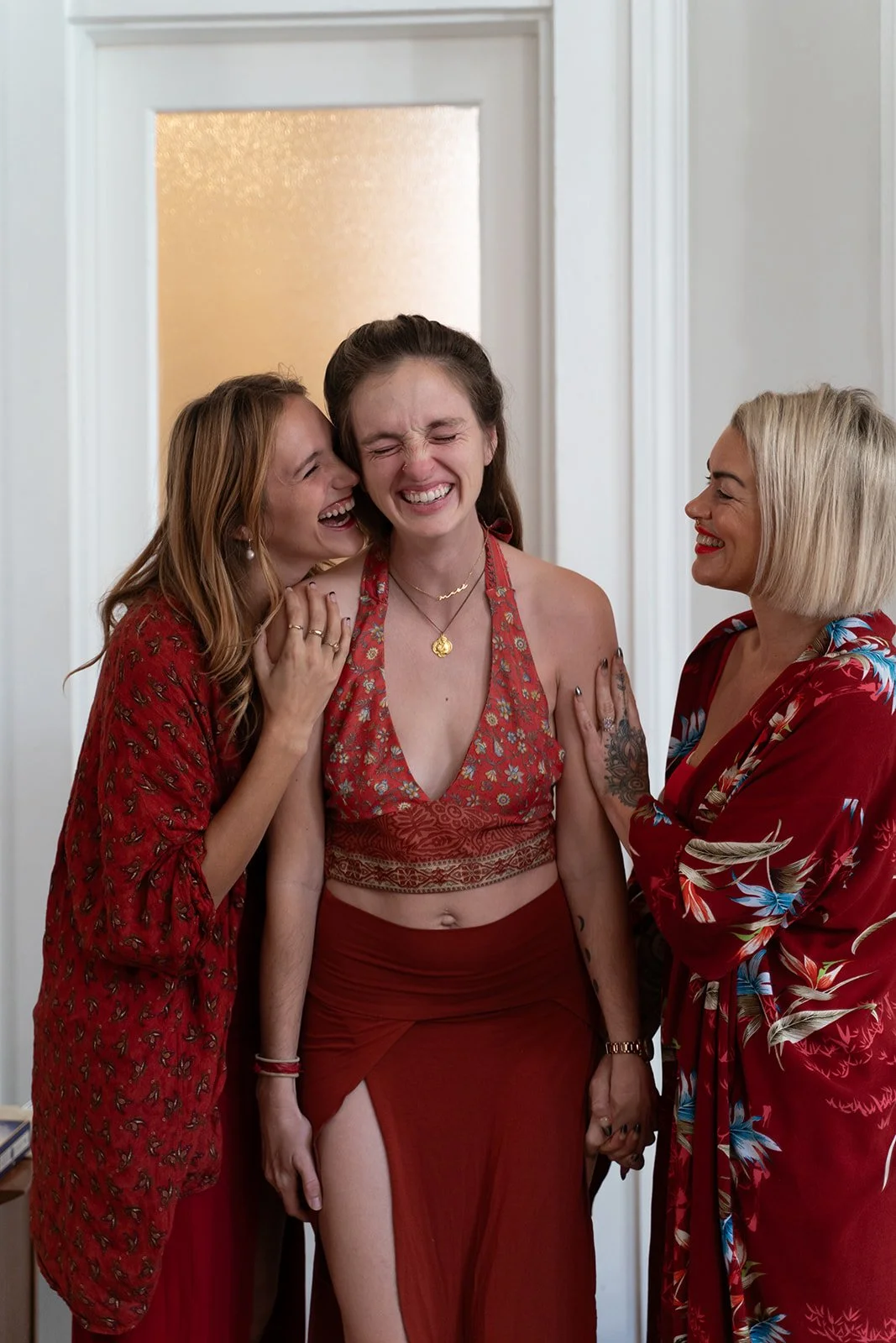 three women in red sharing a special moment the one in the center is receiving praise and crying with joy by photographer Lenee Love