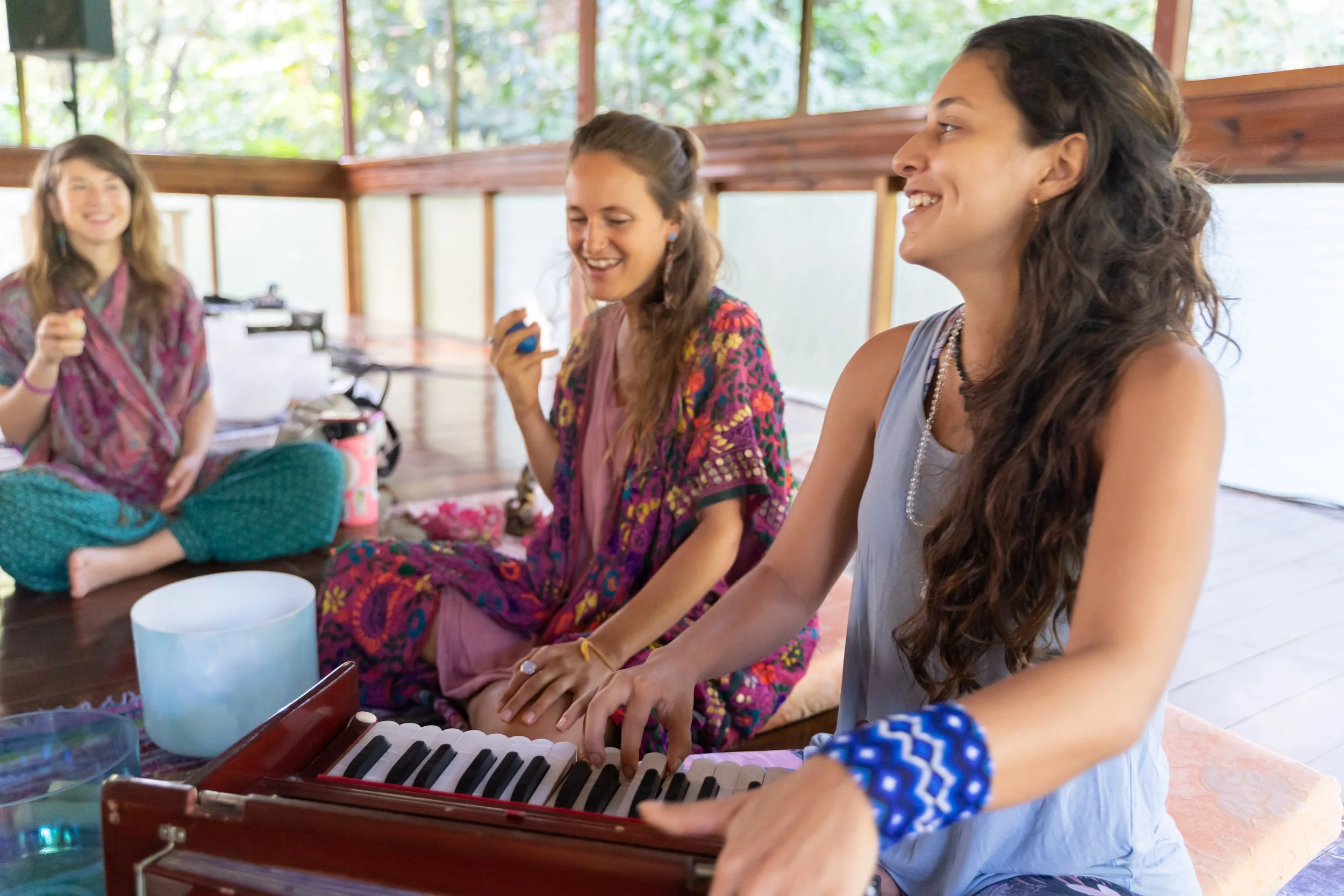 3 women singing and playing music inside a solarium in costa rica at a womens retreat by photographer Lenee Love