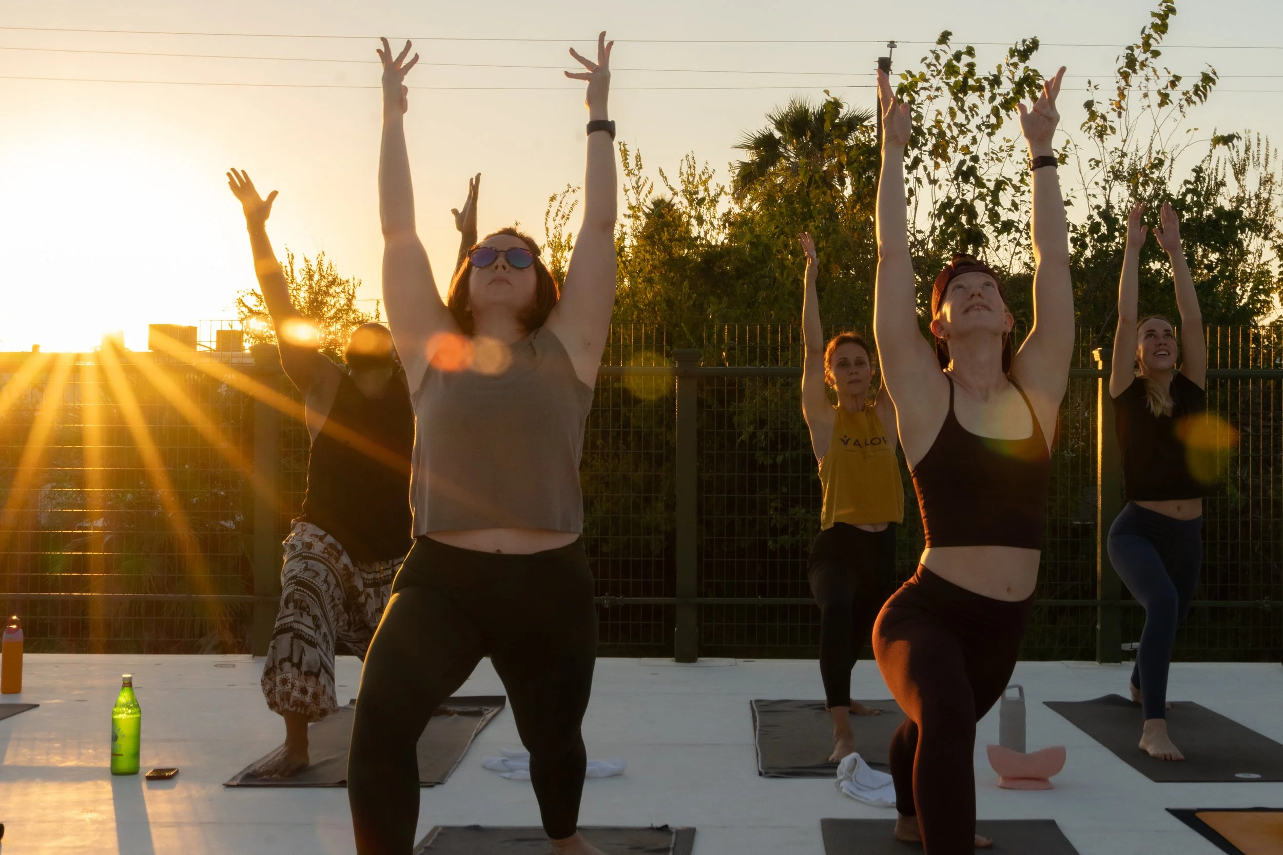 group of yogis doing warrior one on the roof at sunset by yoga photographer Lenee Love