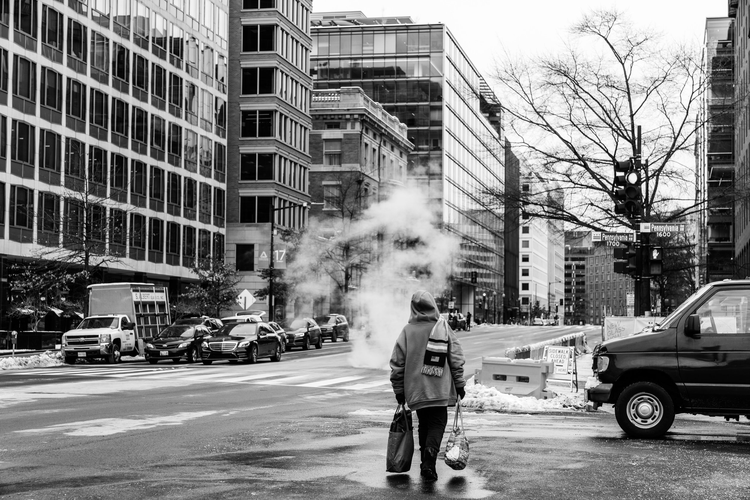 A lady walking down a street in downtown D.C. in black and white.