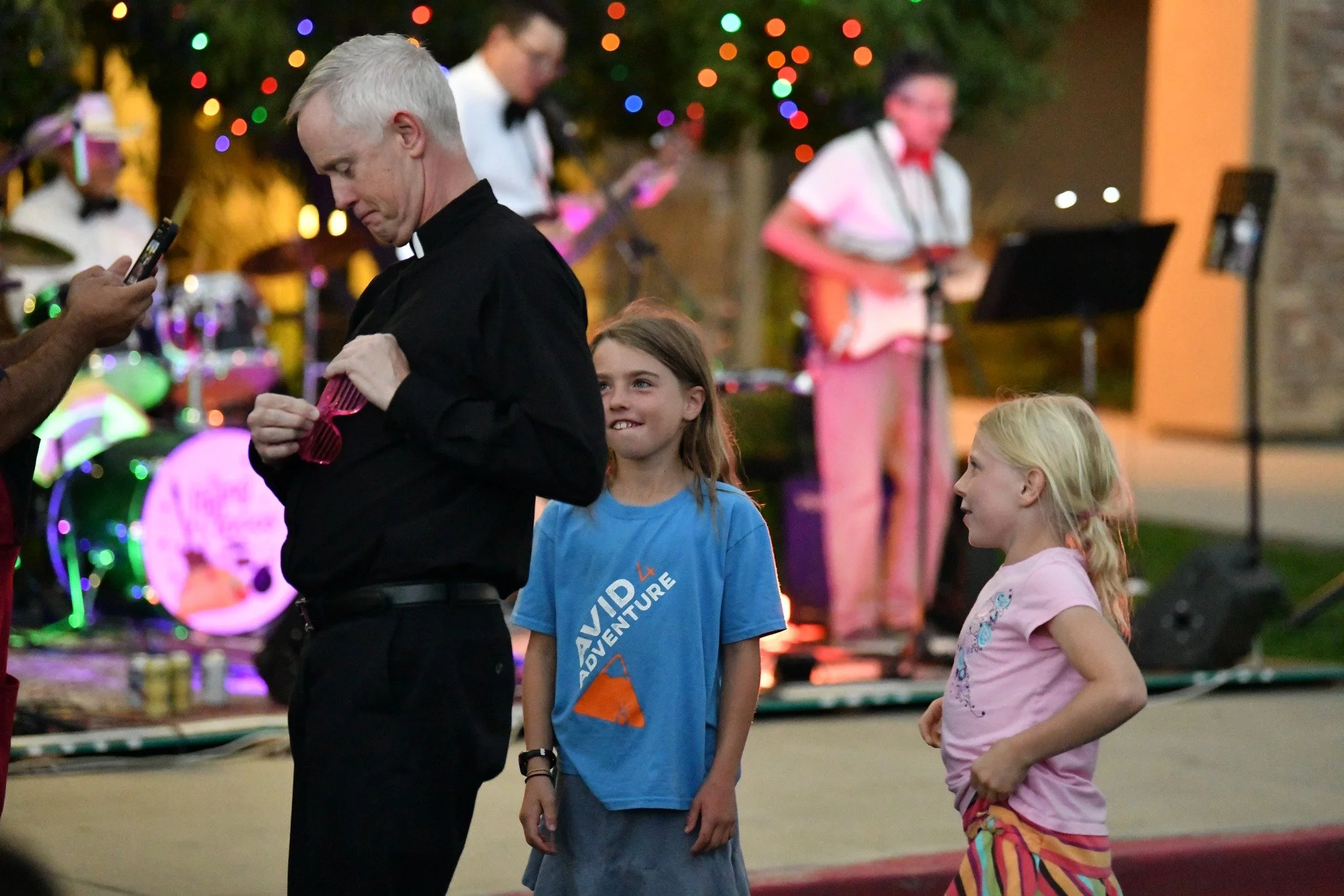 2023: Father Jim Crisman, Pastor, showing a couple of young parishioners how to properly wear the party glasses!