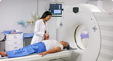 A medical professional prepares a patient for a CT scan in a hospital room.