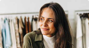 A woman with long brown hair looking to the side in a clothing store