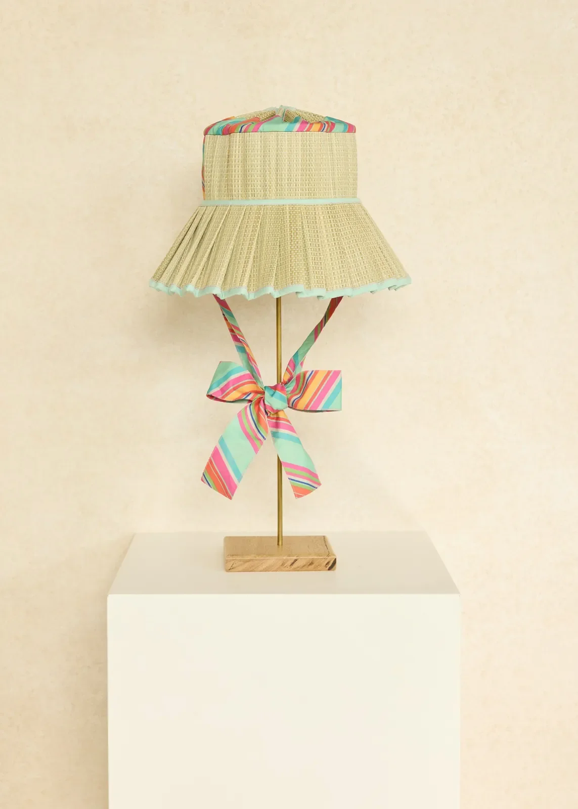 Lorna Murray Pool Float Pacific Luxe Ravello Hat displayed on a stand, highlighting its handcrafted woven design and elegant fabric ties.